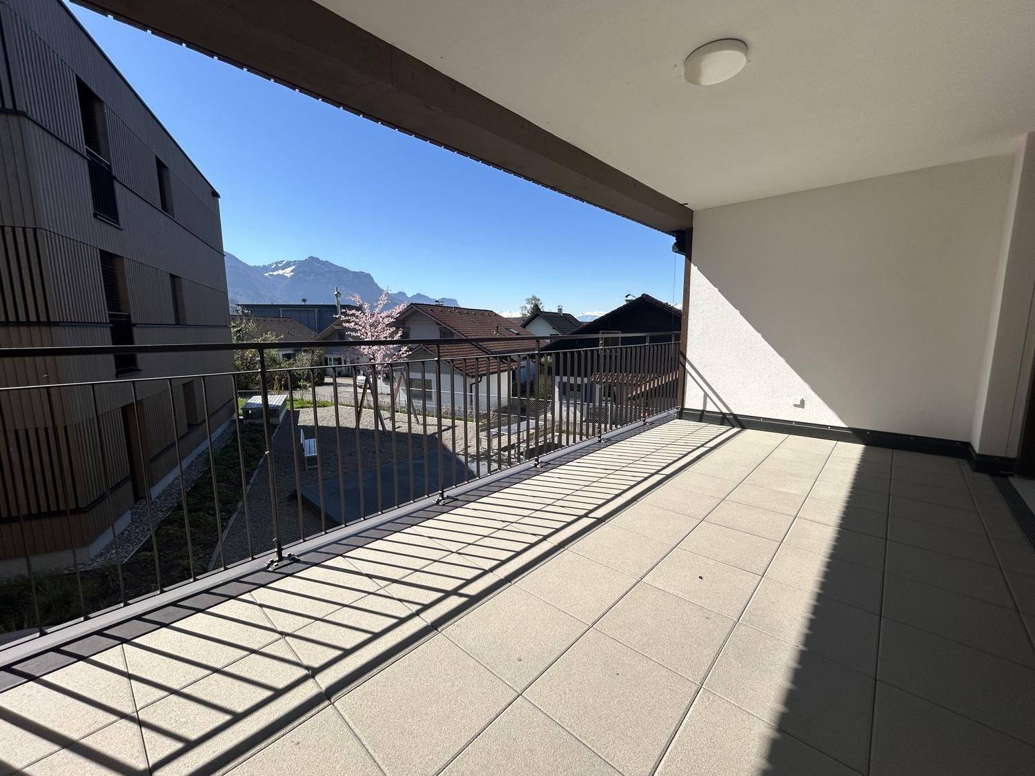 Heller Balkon mit Fliesenboden und schöner Aussicht auf die Berge und die Nachbarschaft.