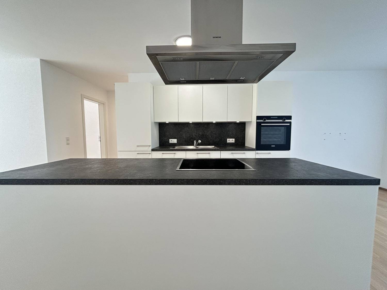 Moderne Küche mit Kochinsel, Induktionskochfeld und integrierten Siemens-Geräten.