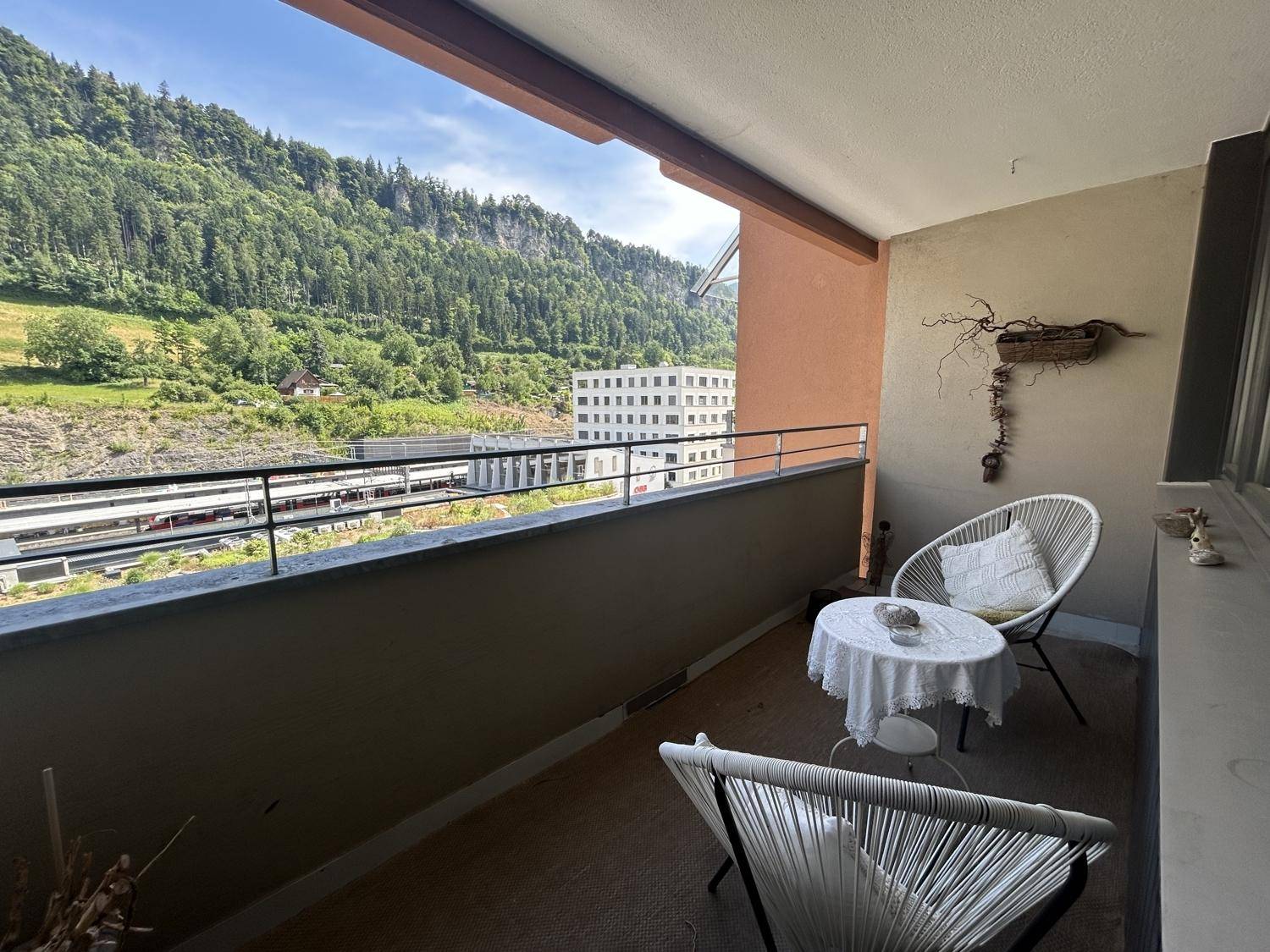 Heller Balkon mit Sitzgelegenheiten und weitem Blick auf die Berge und das Tal.
