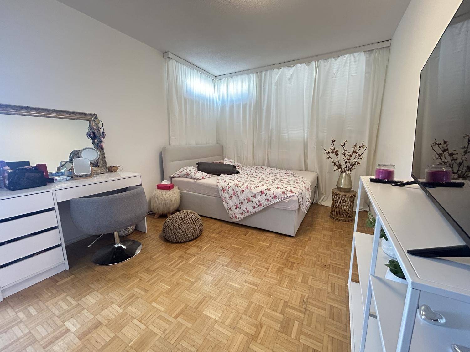 Gemütliches Schlafzimmer mit Parkettboden, großem Bett und einem Schminktisch.