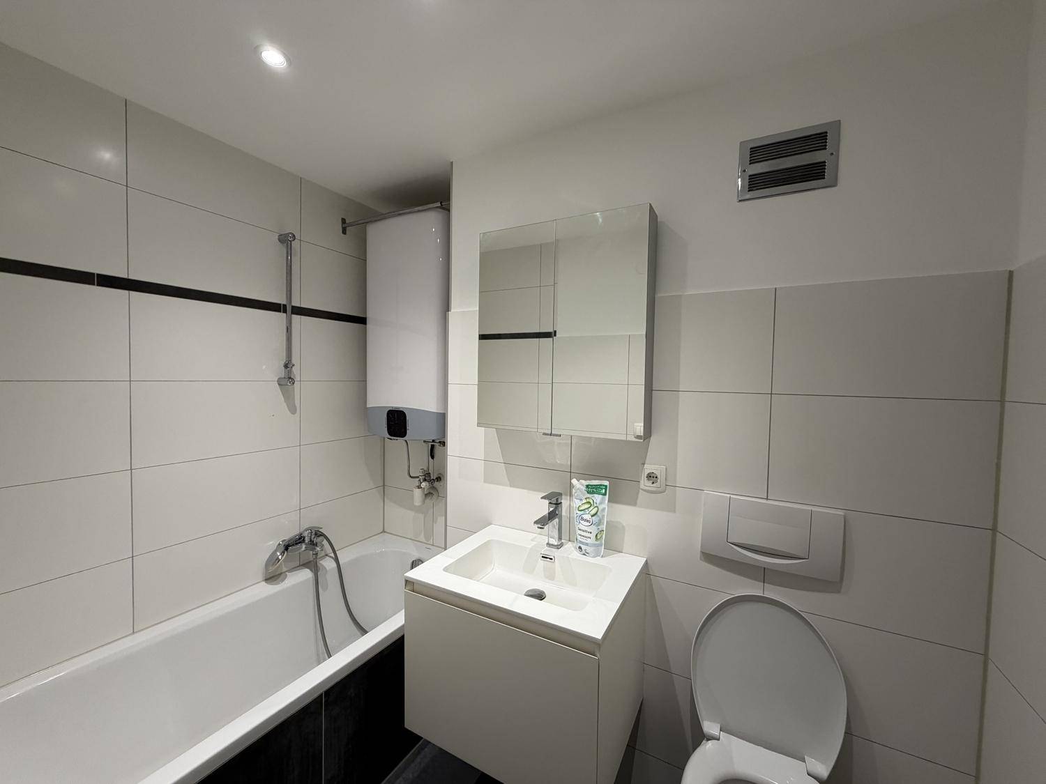 Modern gefliestes Badezimmer mit Badewanne, Dusche, WC und Waschbecken.