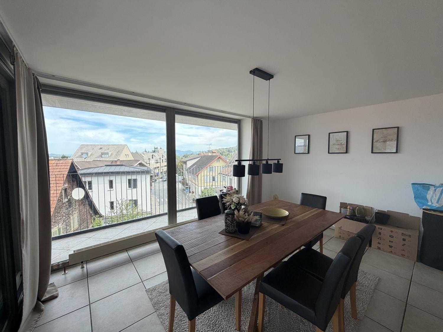 Heller Essbereich mit Holztisch und großen Fenstern, die einen weiten Blick über die Stadt bieten.