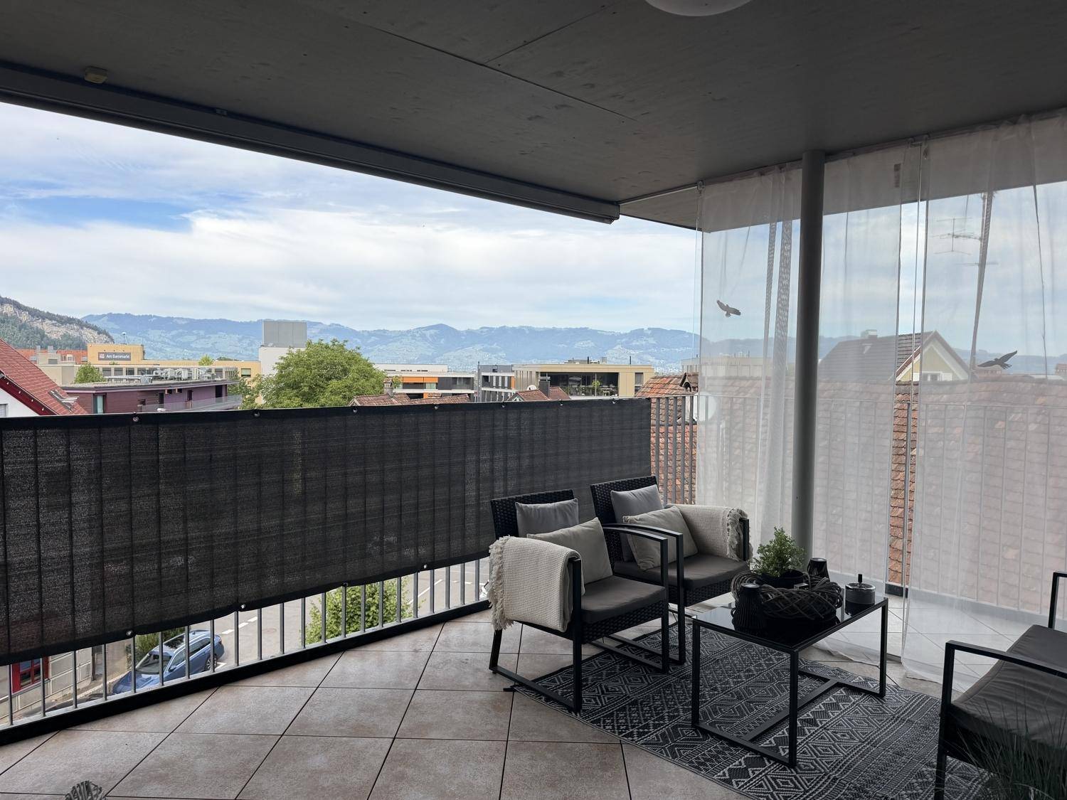Möblierter Balkon mit bequemen Sitzgelegenheiten und einem weiten Blick auf die Berge und die Stadt.