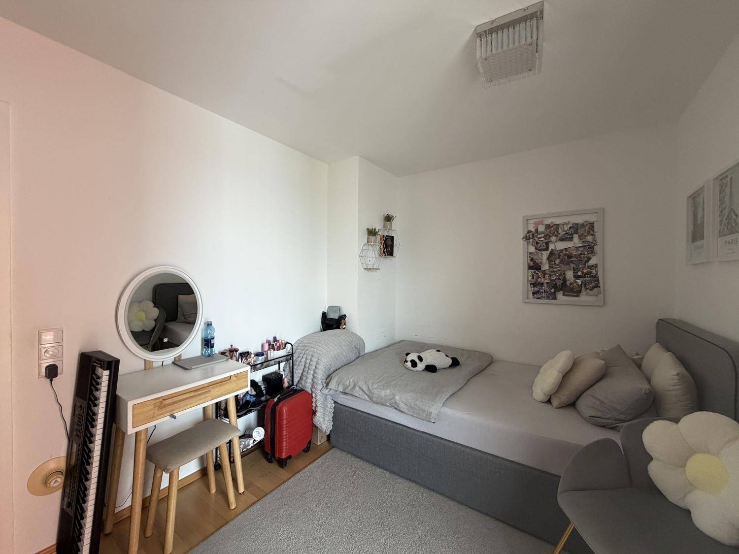 Schlafzimmer mit einem Schminktisch und rundem Spiegel, hell und freundlich eingerichtet.