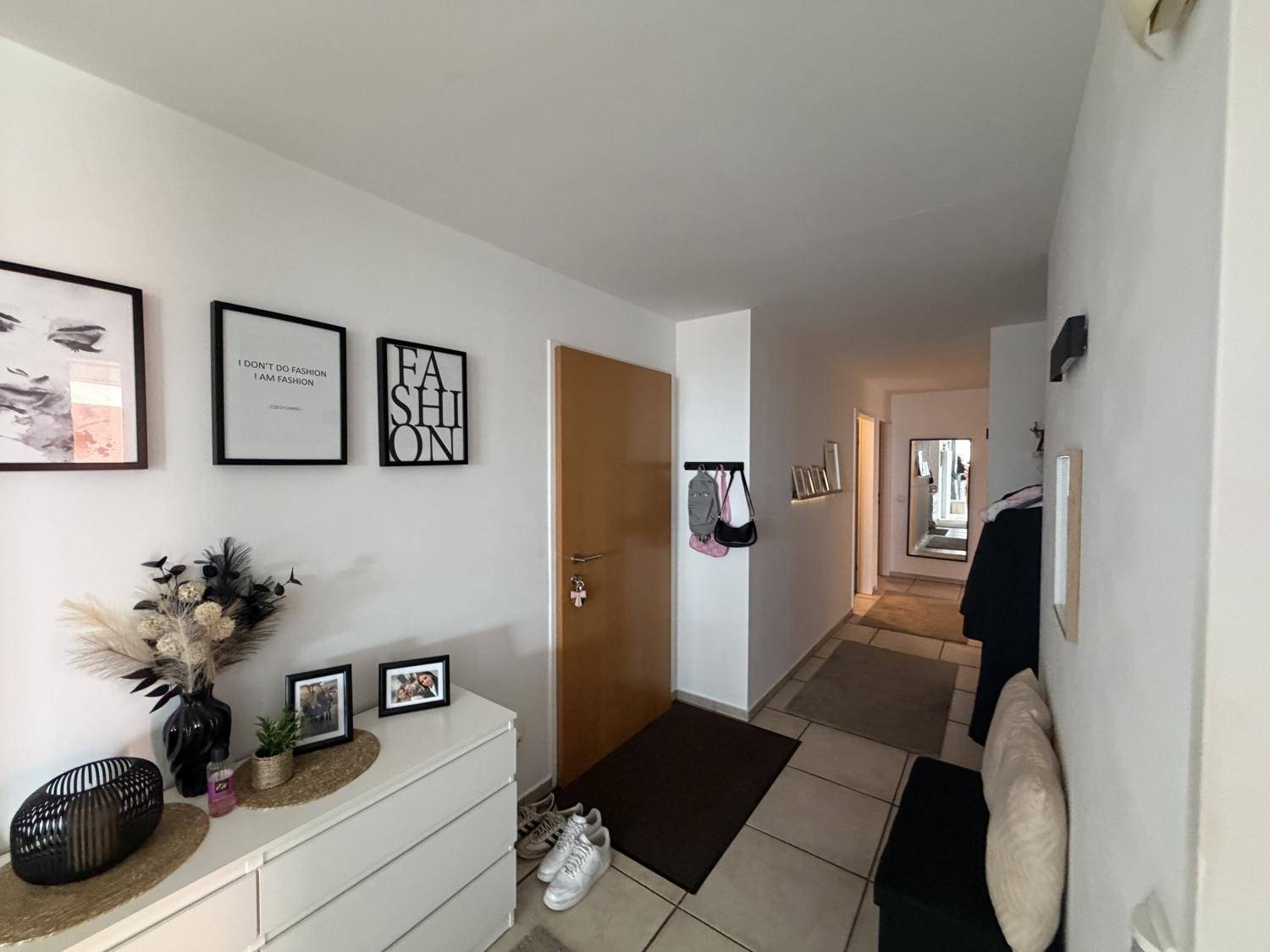 Heller Eingangsbereich mit Kommode, Spiegel und Garderobe, ausgestattet mit Fliesenboden.