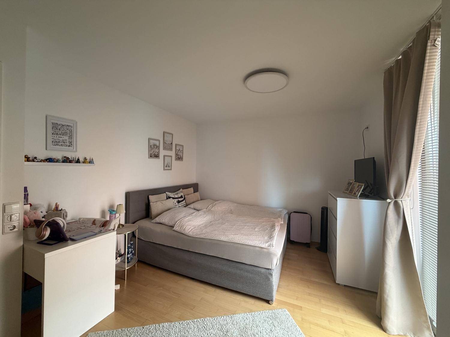 Geräumiges Schlafzimmer mit Doppelbett, Holzboden und großen Fenstern für viel Tageslicht.