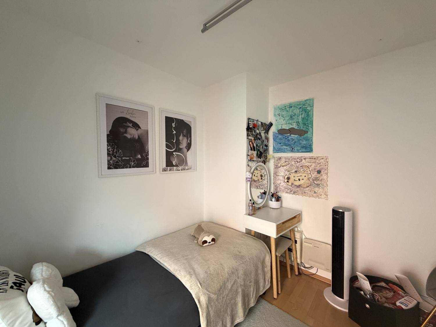 Freundliches Schlafzimmer mit Holzboden, Einzelbett und dekorativen Bildern an der Wand.