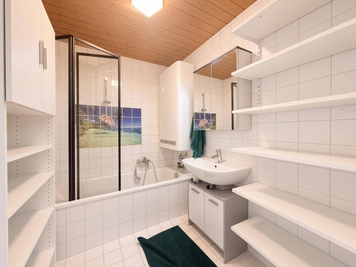 Gefliestes Badezimmer mit Badewanne, Duschabtrennung, Waschbecken und praktischen offenen Regalen.