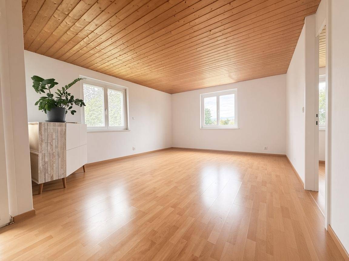 Leeres Wohnzimmer mit warmem Holzdecken- und Parkettboden, großen Fenstern und viel natürlichem Licht.