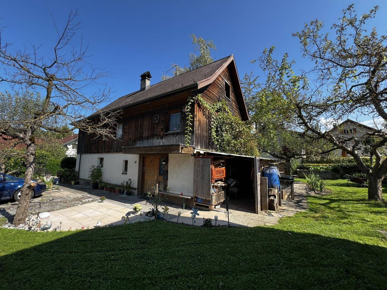 Rückansicht des Hauses mit großem Garten, Rasenfläche und einem überdachten Bereich.