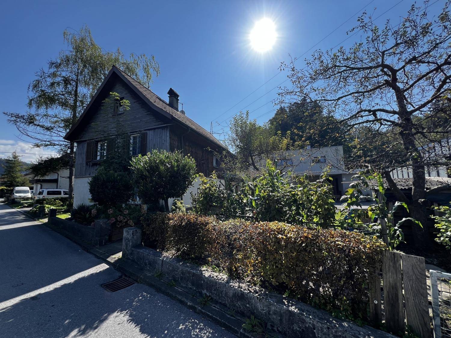 Charmantes Holzhaus mit traditioneller Architektur und üppiger Bepflanzung im Vorgarten.