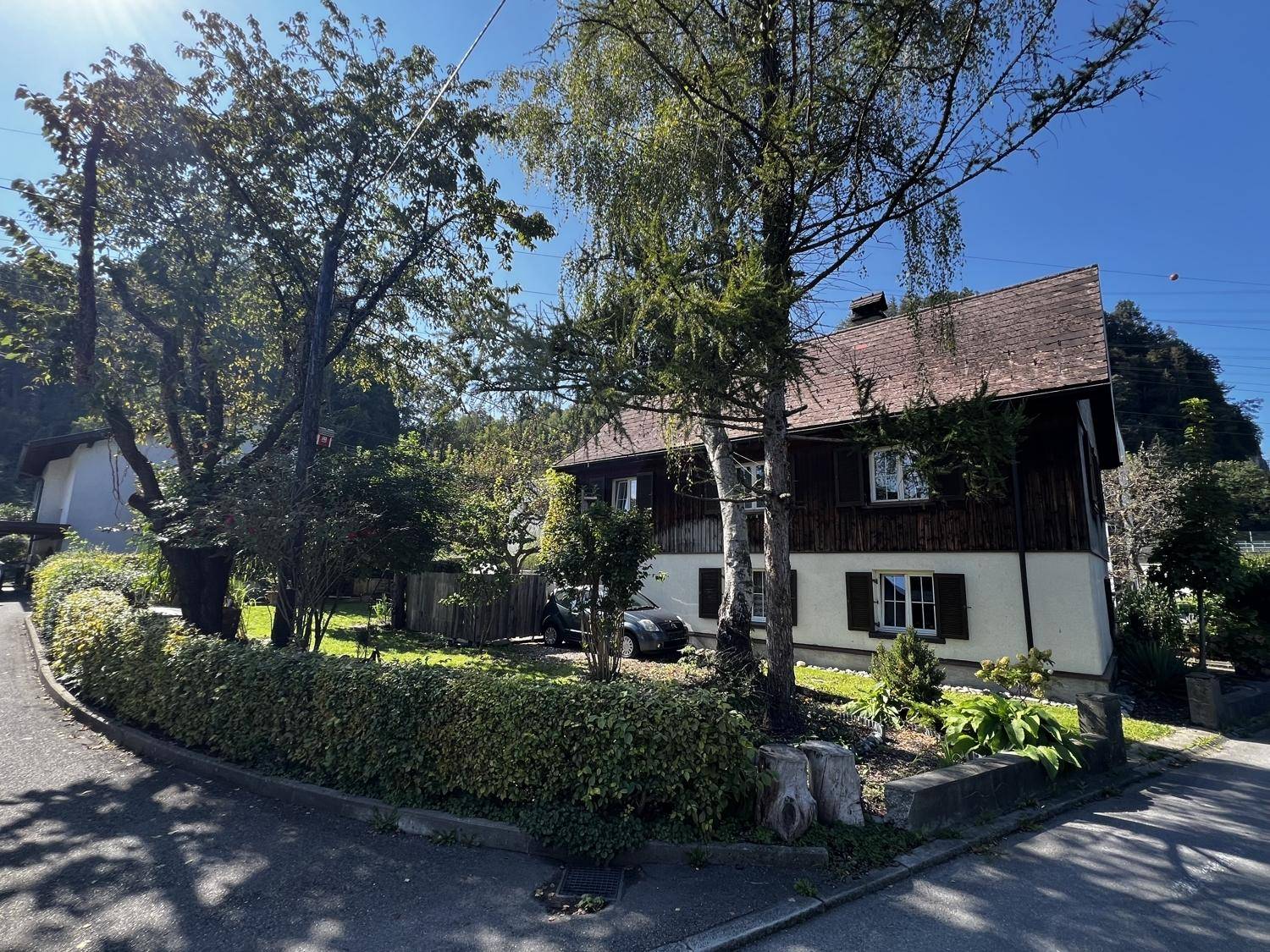 Idyllisches Wohnhaus umgeben von Bäumen und Hecken an einer ruhigen Seitenstraße gelegen.