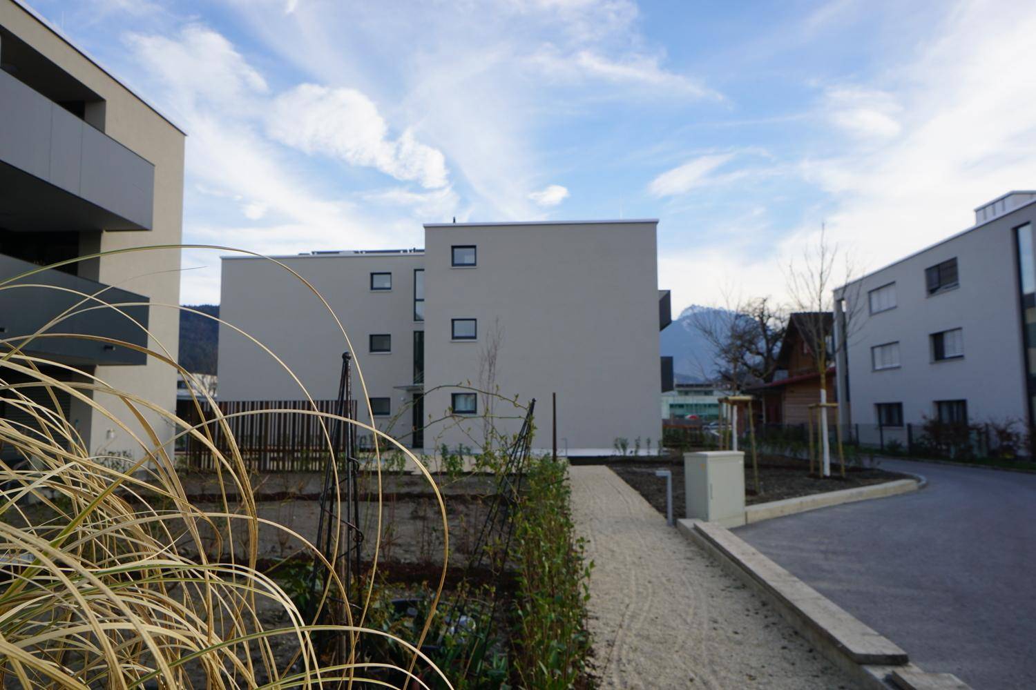 Moderne Wohngebäude in einer ruhigen Umgebung mit Blick auf die Berge unter blauem Himmel.