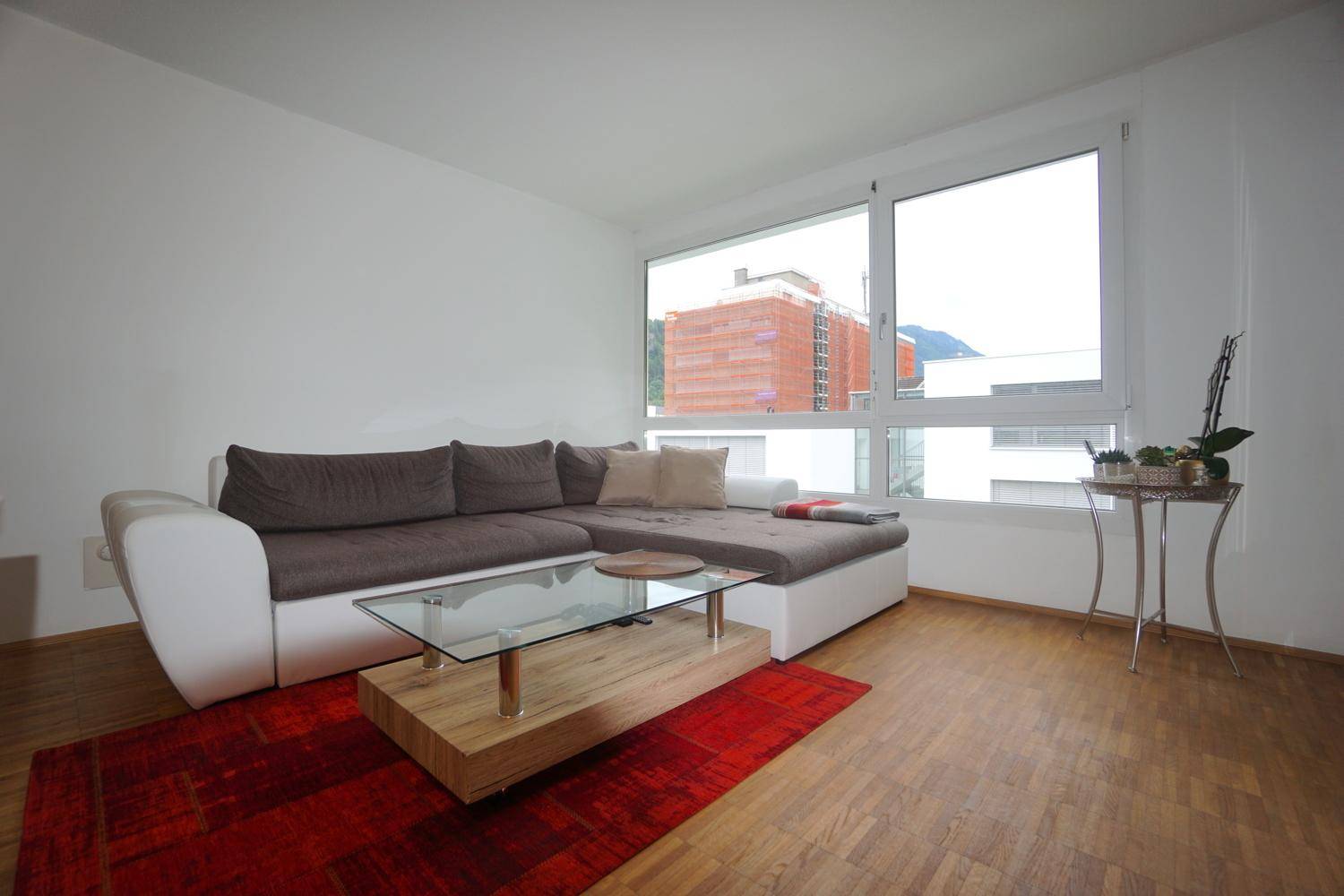 Gemütlicher Wohnbereich mit Ecksofa, Couchtisch und großen Fenstern für viel Helligkeit.