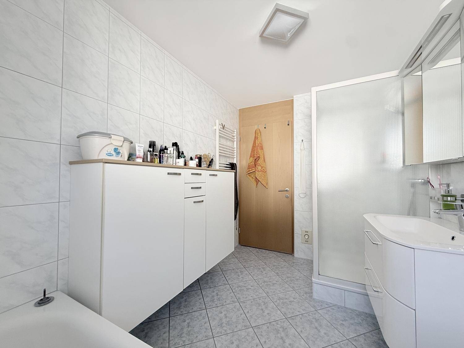 Funktionales Badezimmer mit Dusche, Badewanne und praktischem Stauraum.