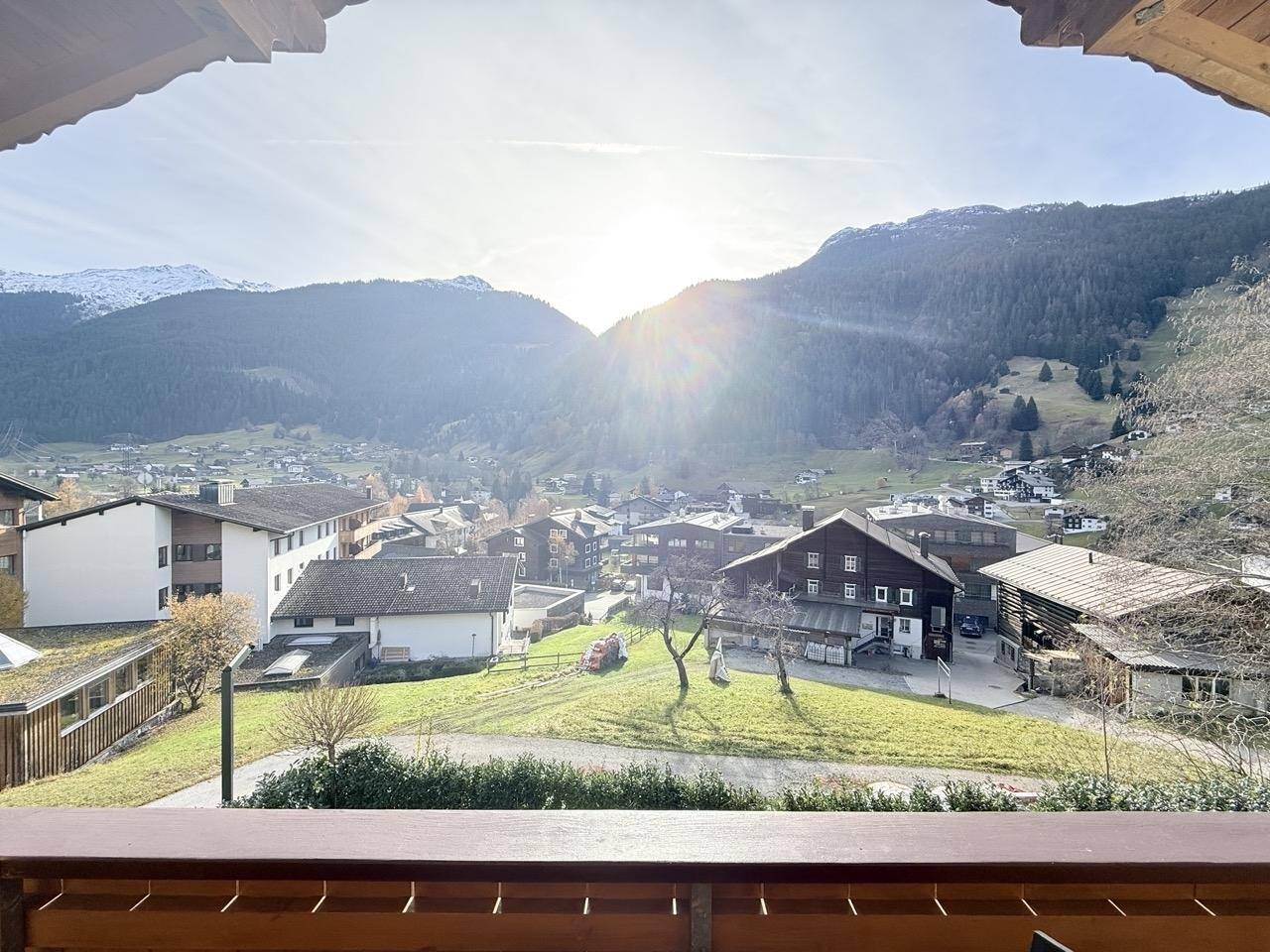 Sonniger Balkon mit weitem Blick über das Dorf und die umliegende Berglandschaft.