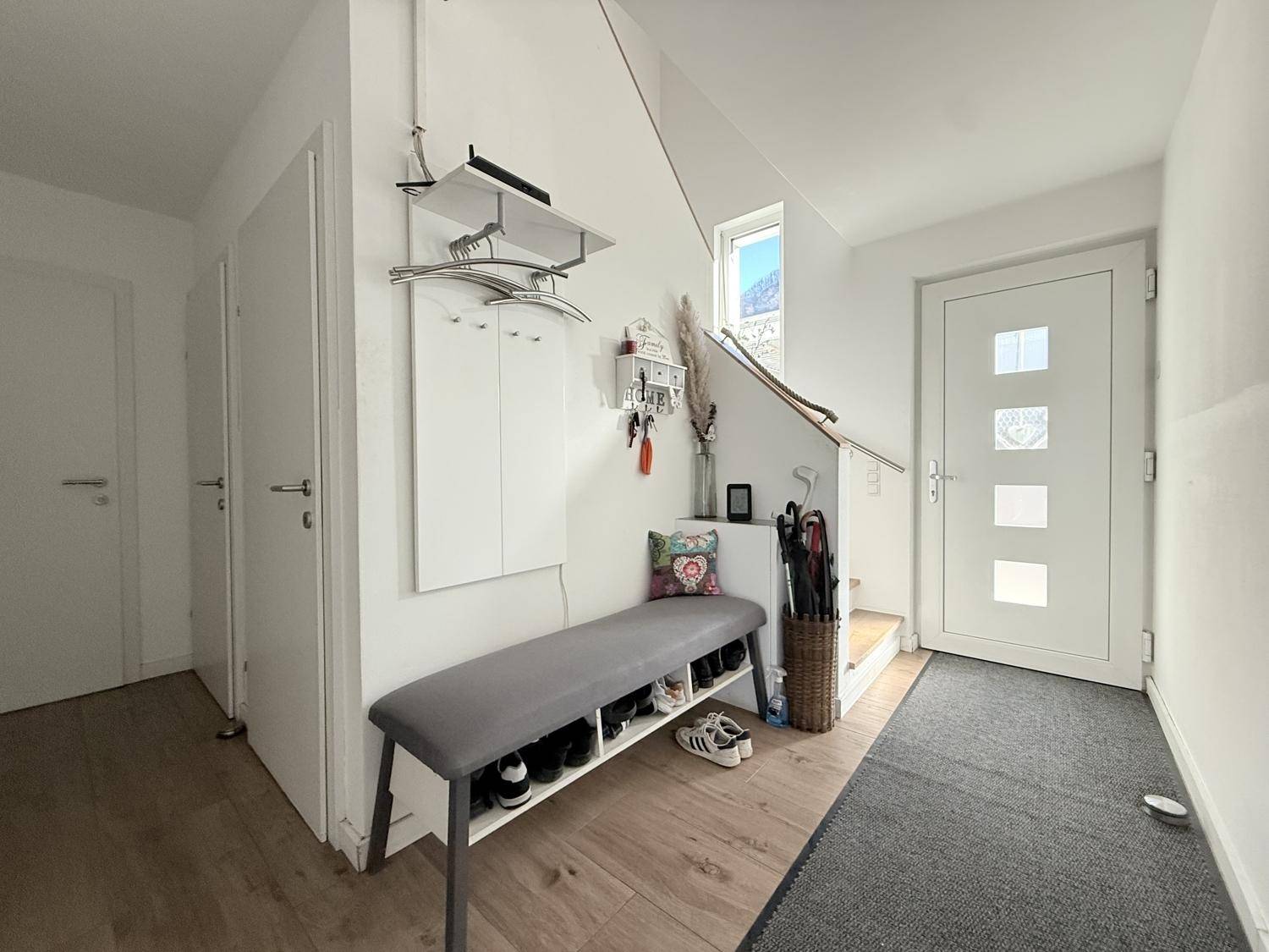 Eingangsbereich mit Garderobe, Schuhbank und heller Eingangstür.
