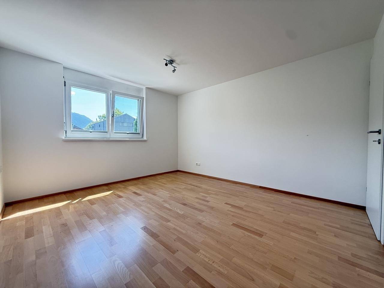 Geräumiges Schlafzimmer mit viel Tageslicht und einem gepflegten Holzfußboden.