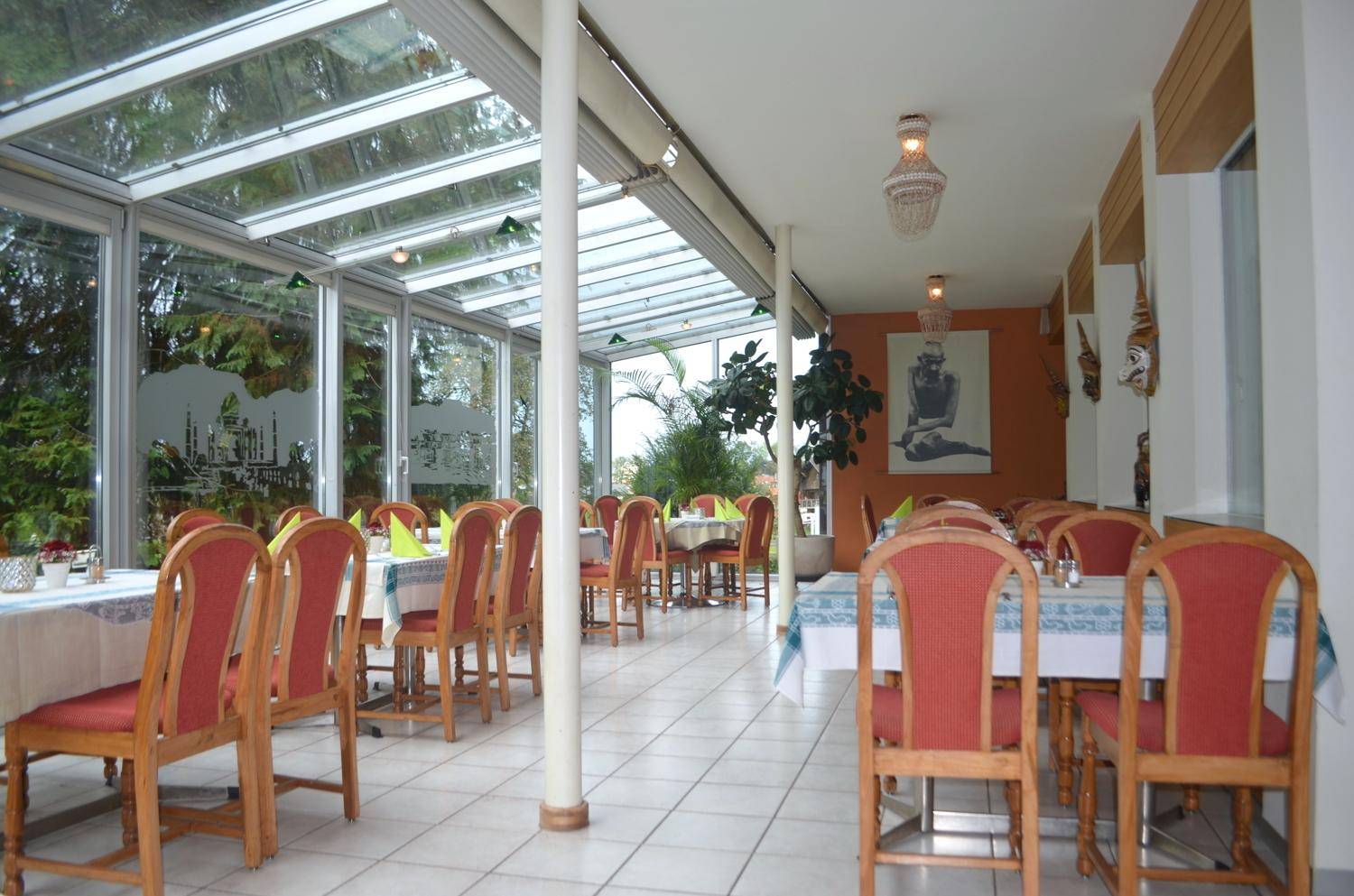 Heller Wintergarten-Essbereich mit Glasdach, großen Fenstern und vielen Sitzgelegenheiten.
