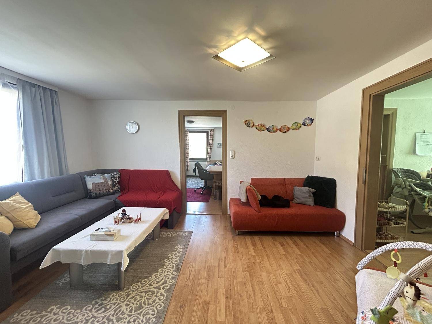 Helles Wohnzimmer mit zwei Sofas und Holzboden, bietet Zugang zu einem weiteren Raum.