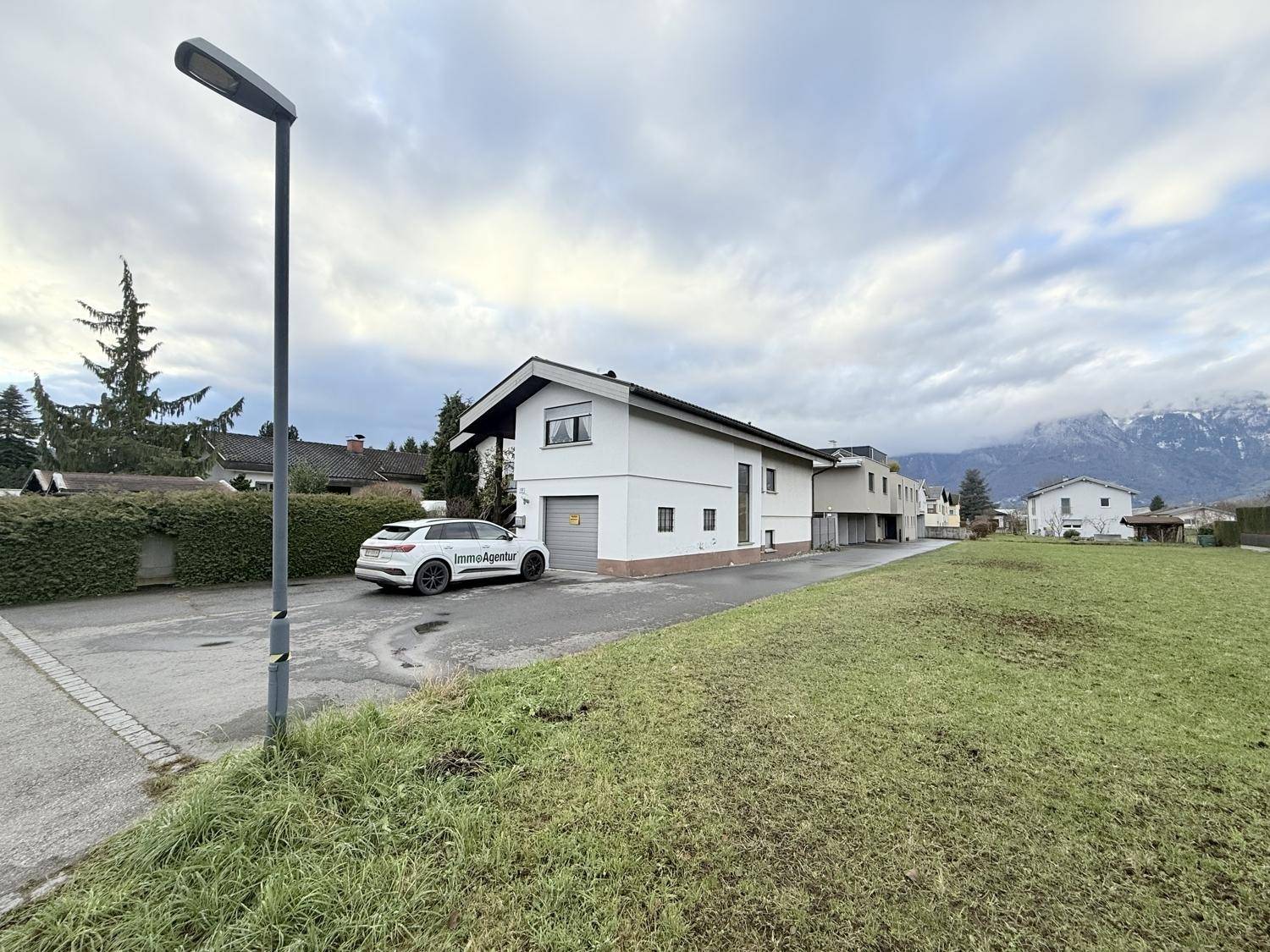 Das Haus in ländlicher Umgebung mit weiten Grünflächen und einer beeindruckenden Bergkulisse.