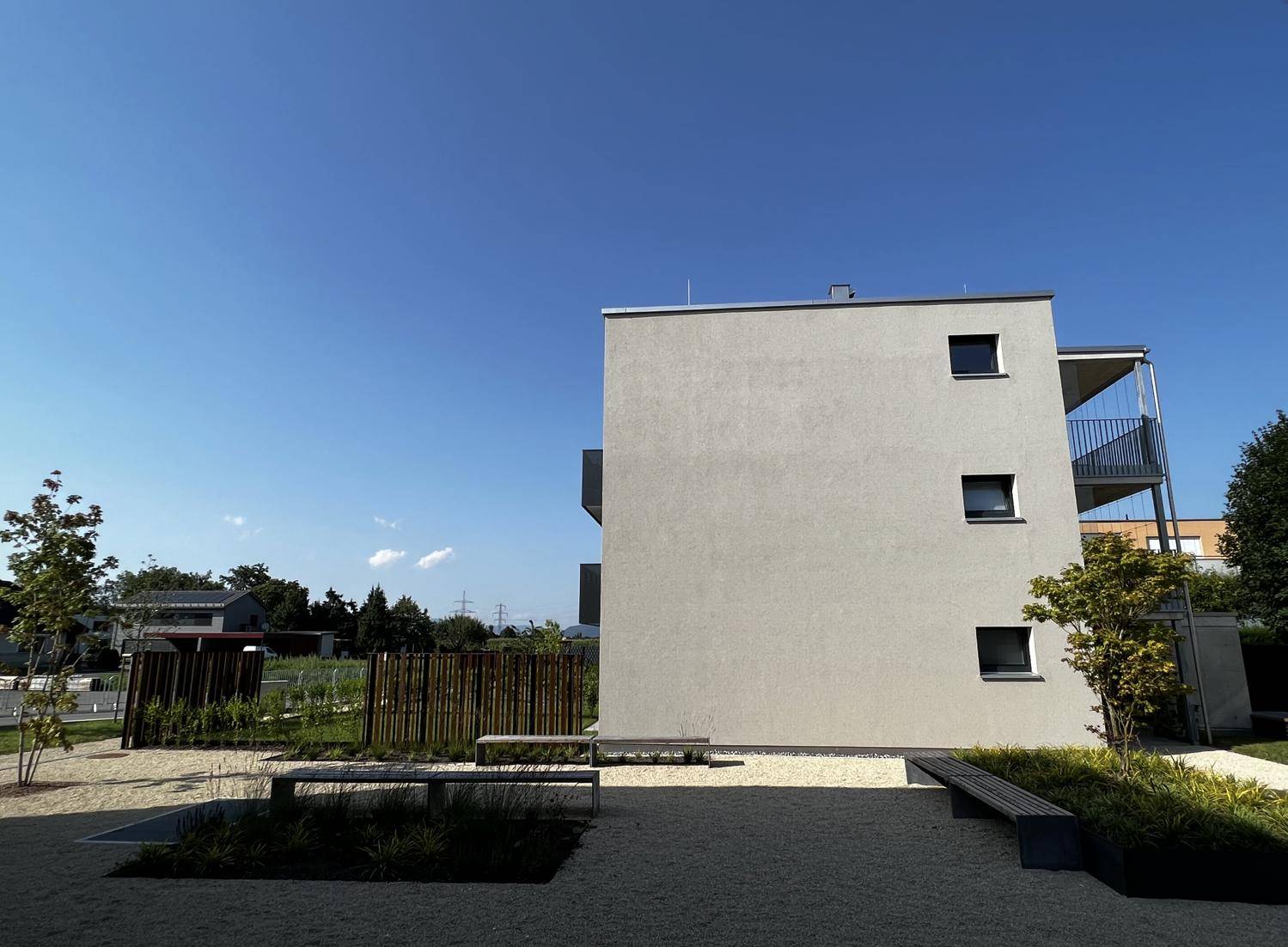Seitenansicht eines modernen Wohngebäudes mit kleinen Fenstern und Außenbereich.