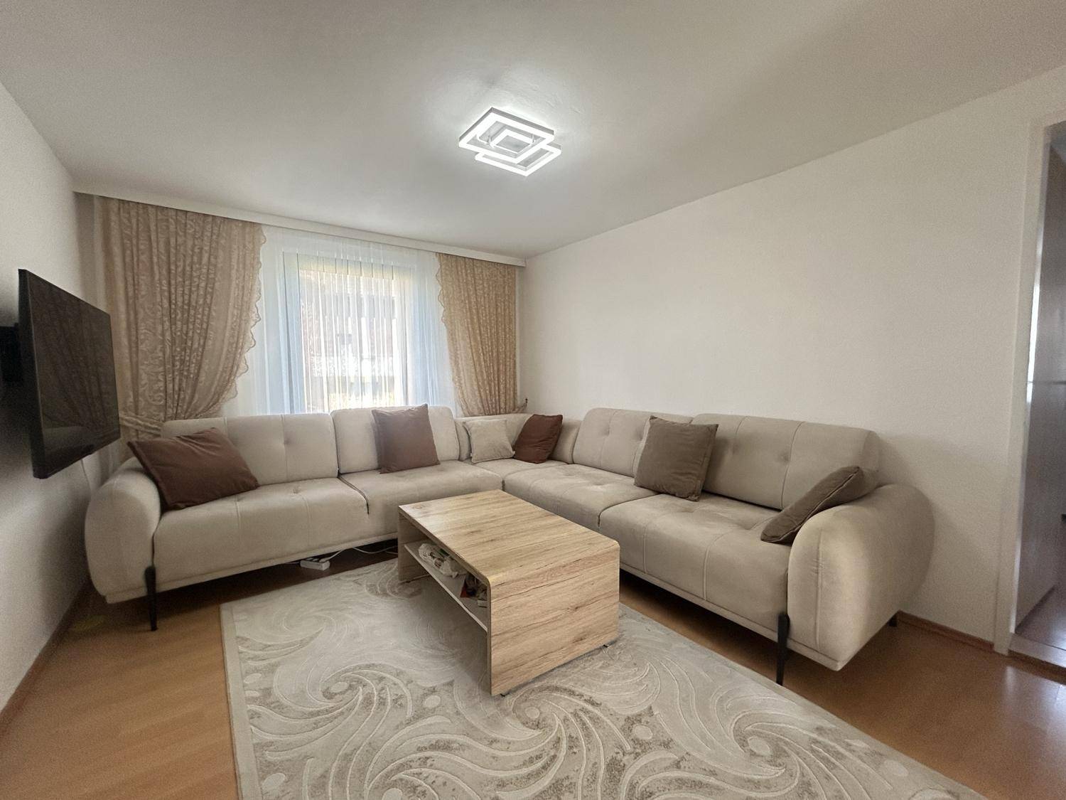 Helles Wohnzimmer mit großem Ecksofa, Couchtisch und Teppich, ideal für entspannte Stunden.
