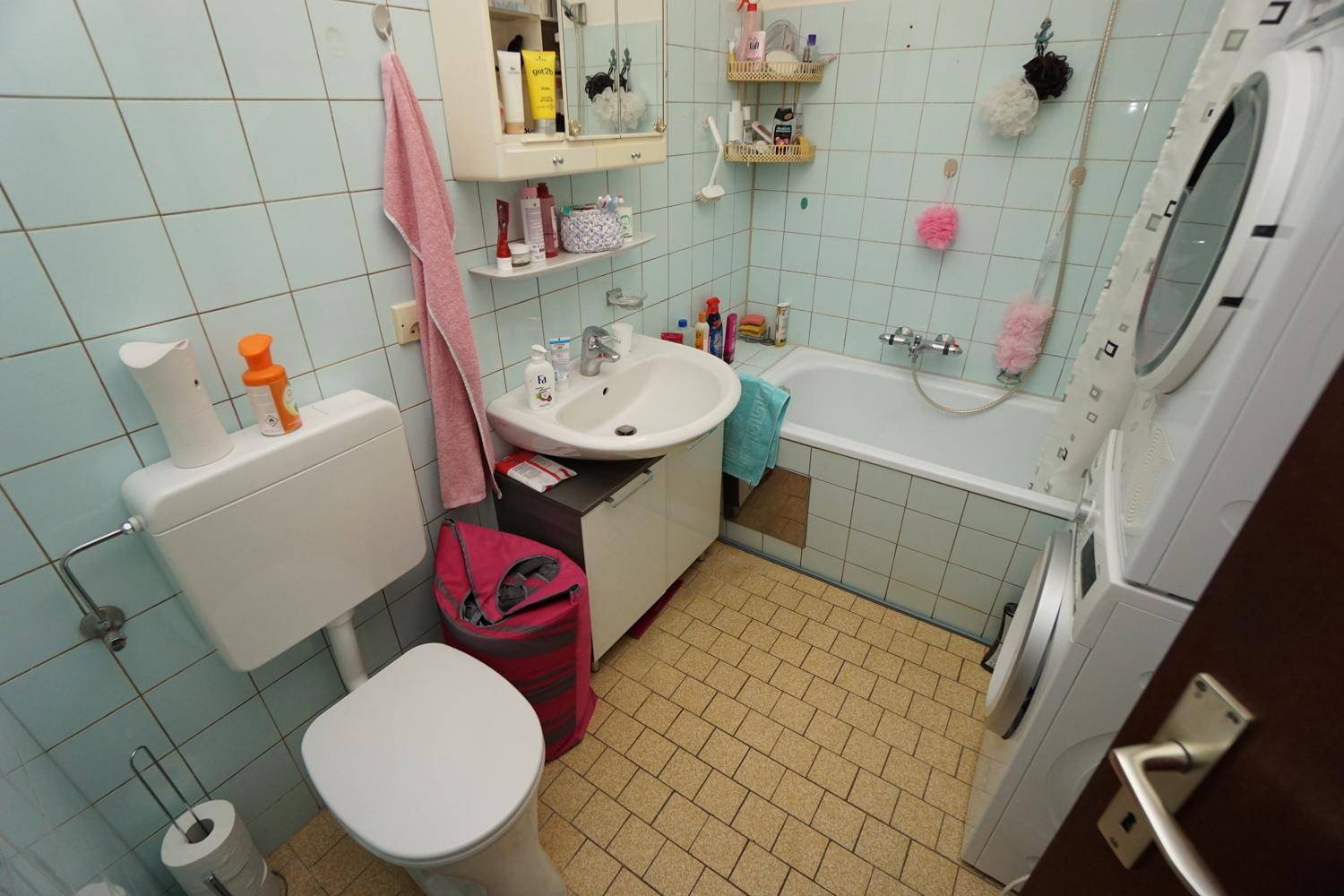 Kleine Küche mit weißen Schränken, Edelstahlspüle, Herd und grünen Wandfliesen.