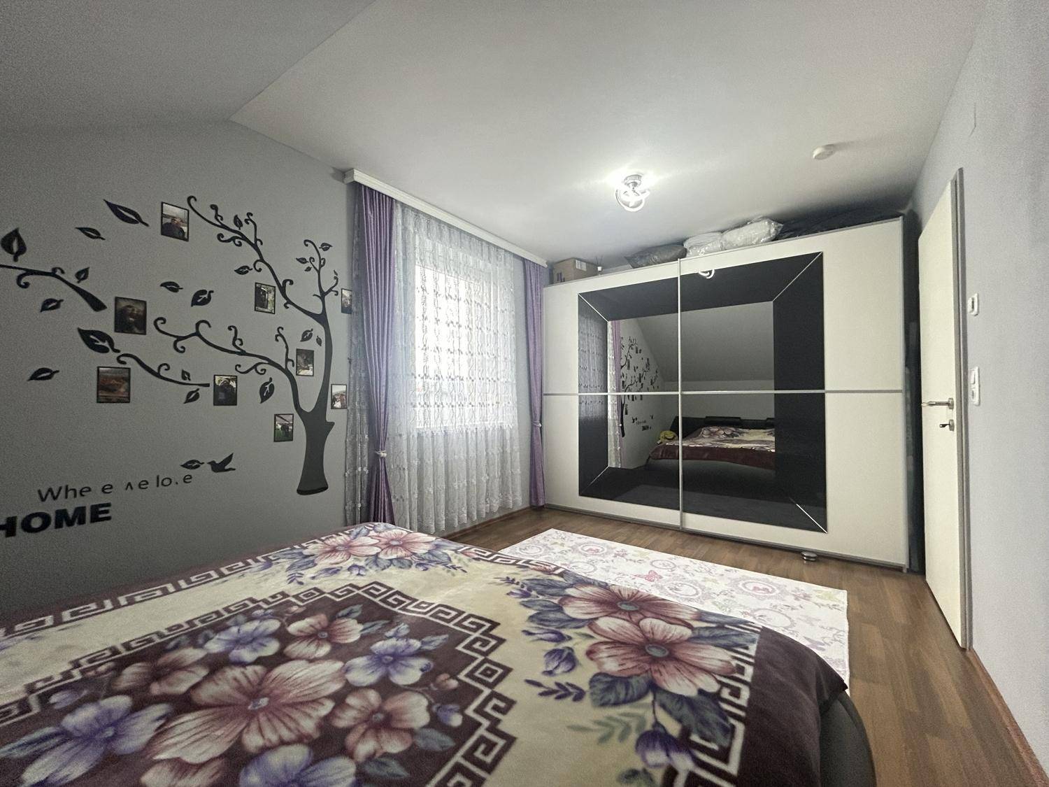 Schlafzimmer mit Doppelbett, großem Spiegelschrank und dekorativer Wandgestaltung, gemütlich eingerichtet.