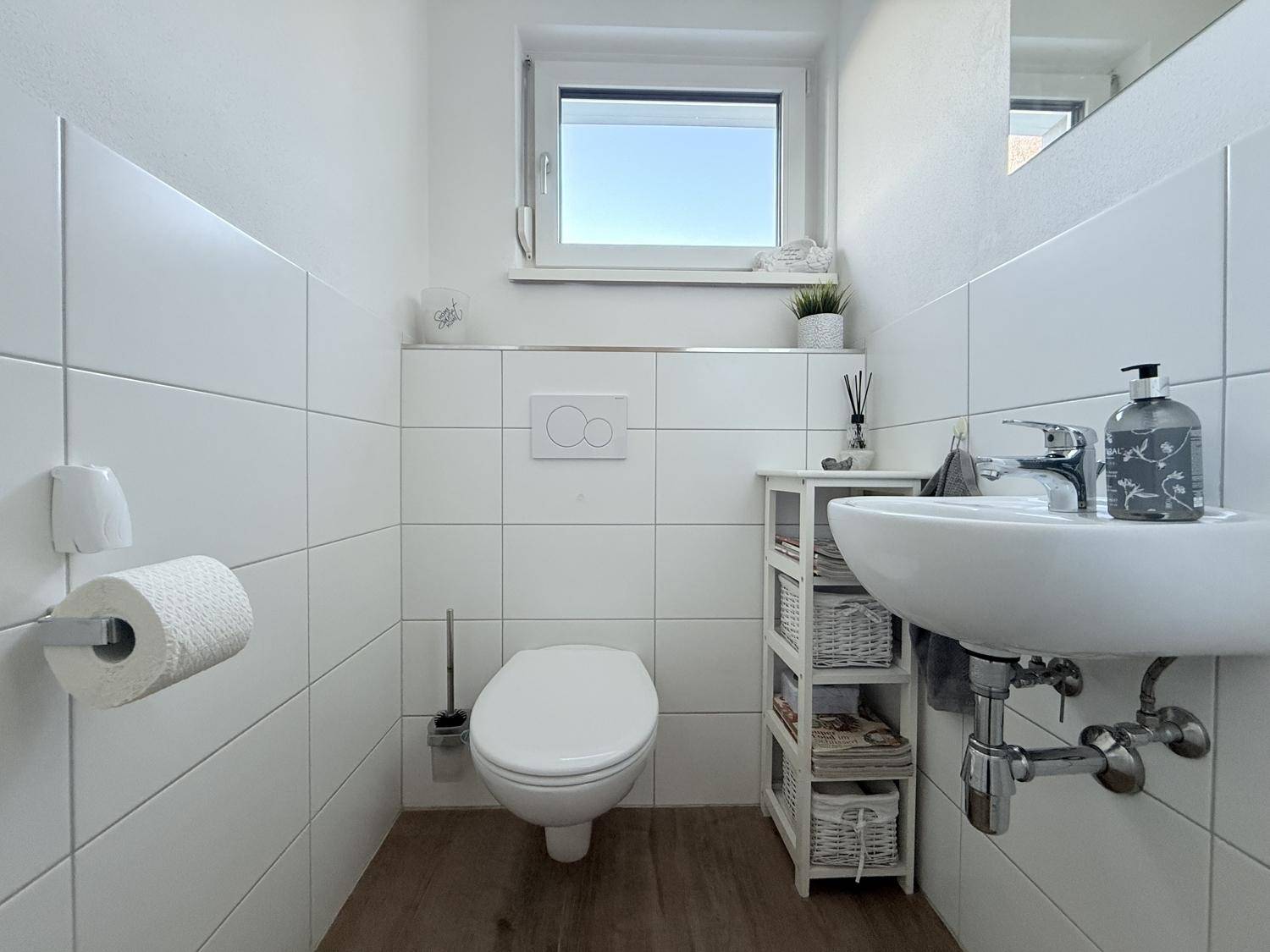 Modernes Gäste-WC mit Fenster, Wand-WC und kleinem Waschbecken.