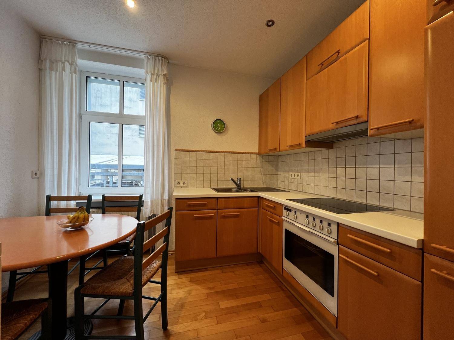 Funktionale Küche mit Holzelementen, Essbereich und Fenster für natürliches Licht beim Kochen und Essen.
