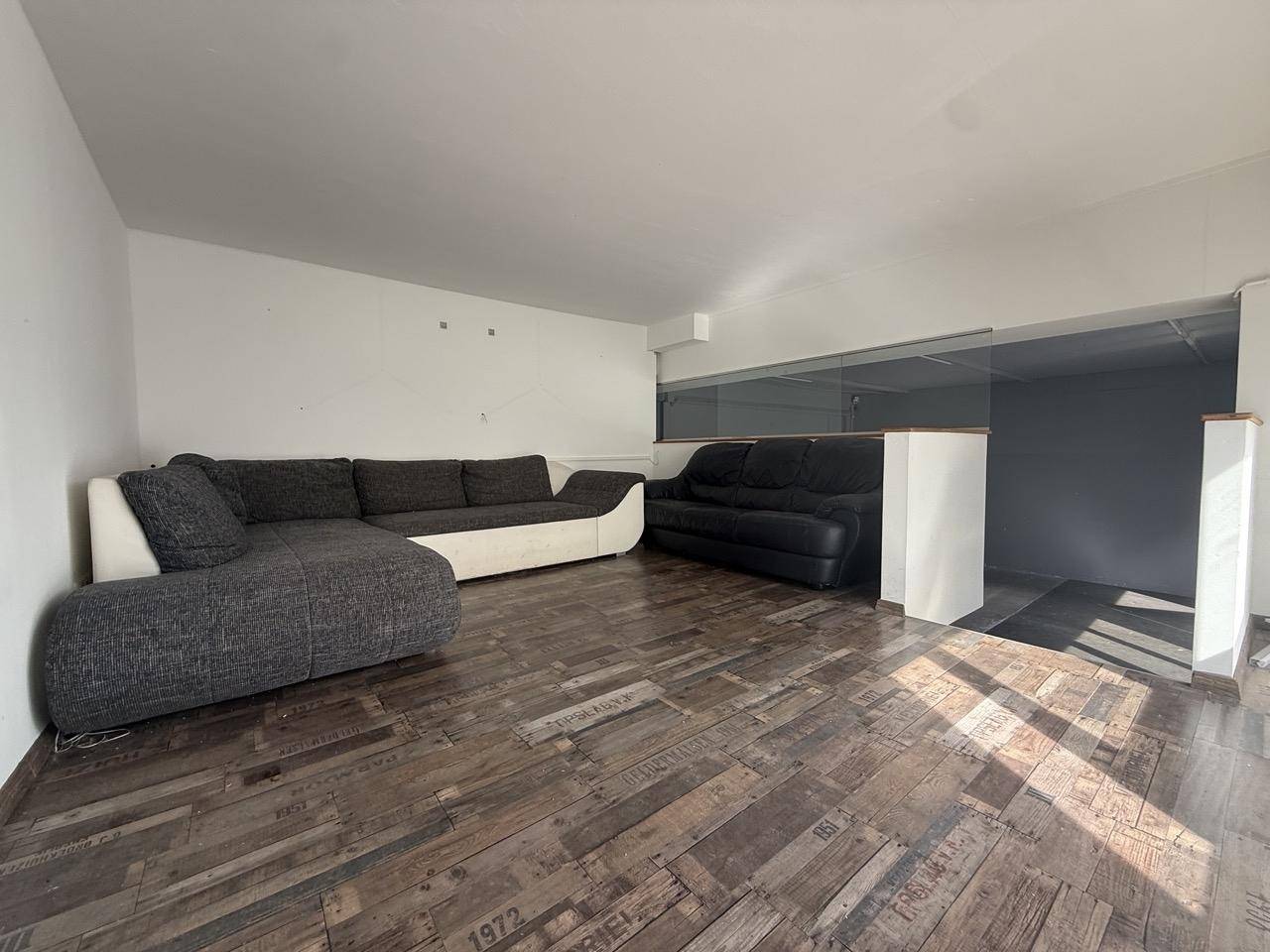 Heller Wohnbereich mit modernem Ecksofa und stilvollem Holzboden auf der oberen Ebene.