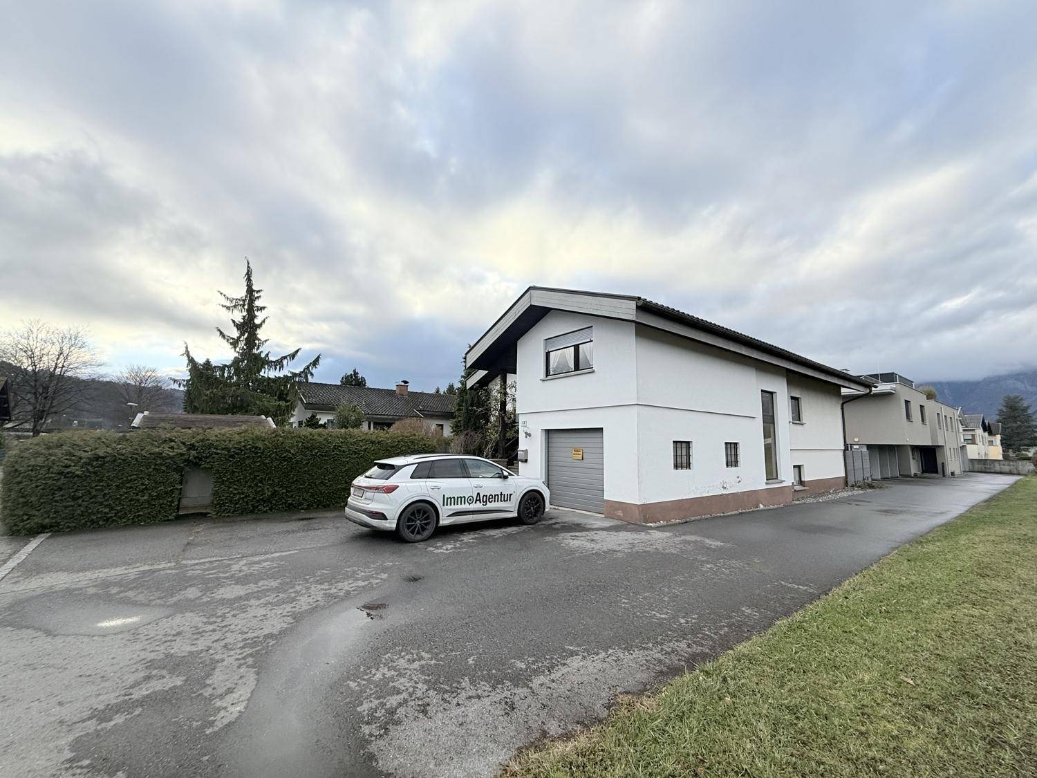 Seitenansicht des Hauses mit Garage und angrenzender Straße, eingebettet in die Umgebung.