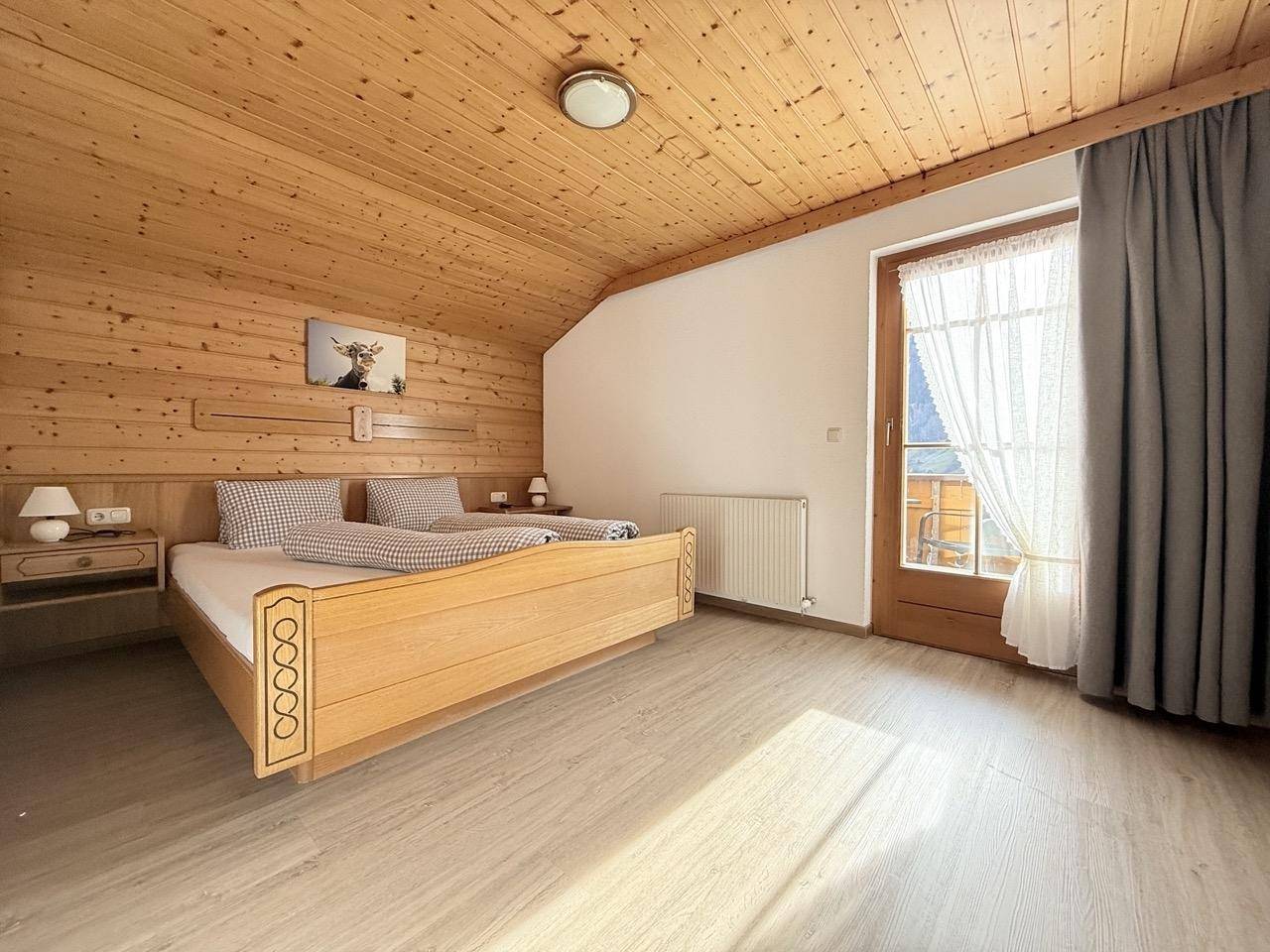 Helles Schlafzimmer mit Holzdecken, Holzwänden und direktem Zugang zum Balkon.