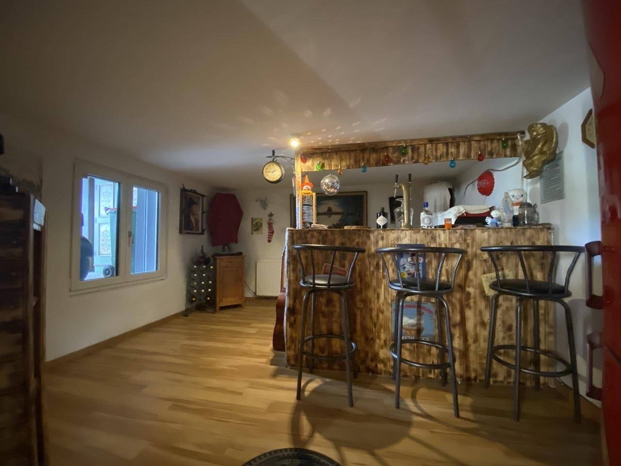 Gemütlicher Hobbyraum mit Bar, Holzboden und indirekter Beleuchtung.