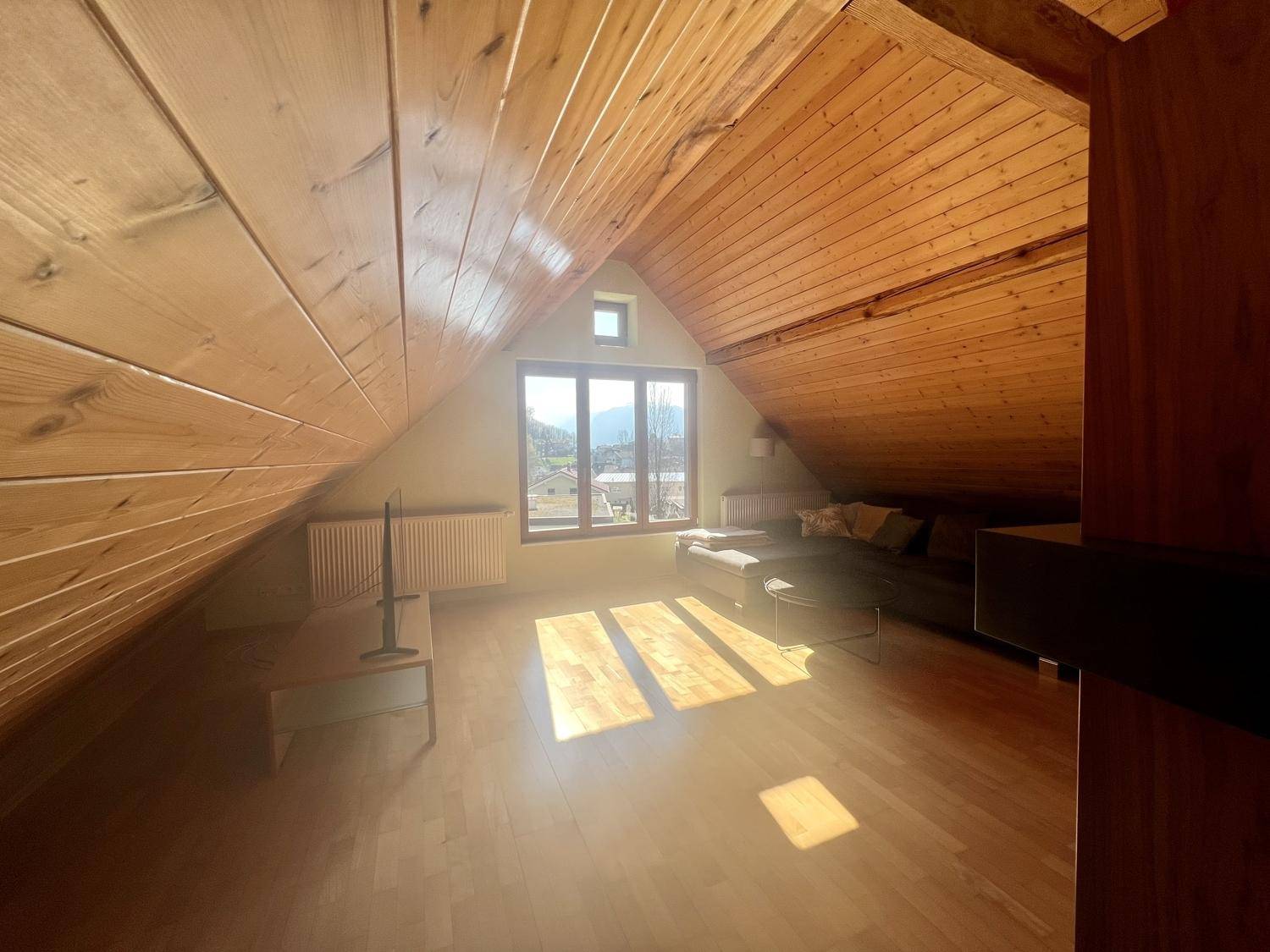 Ausgebauter Dachboden mit Holztäfelung, großen Fenstern und viel Tageslicht.