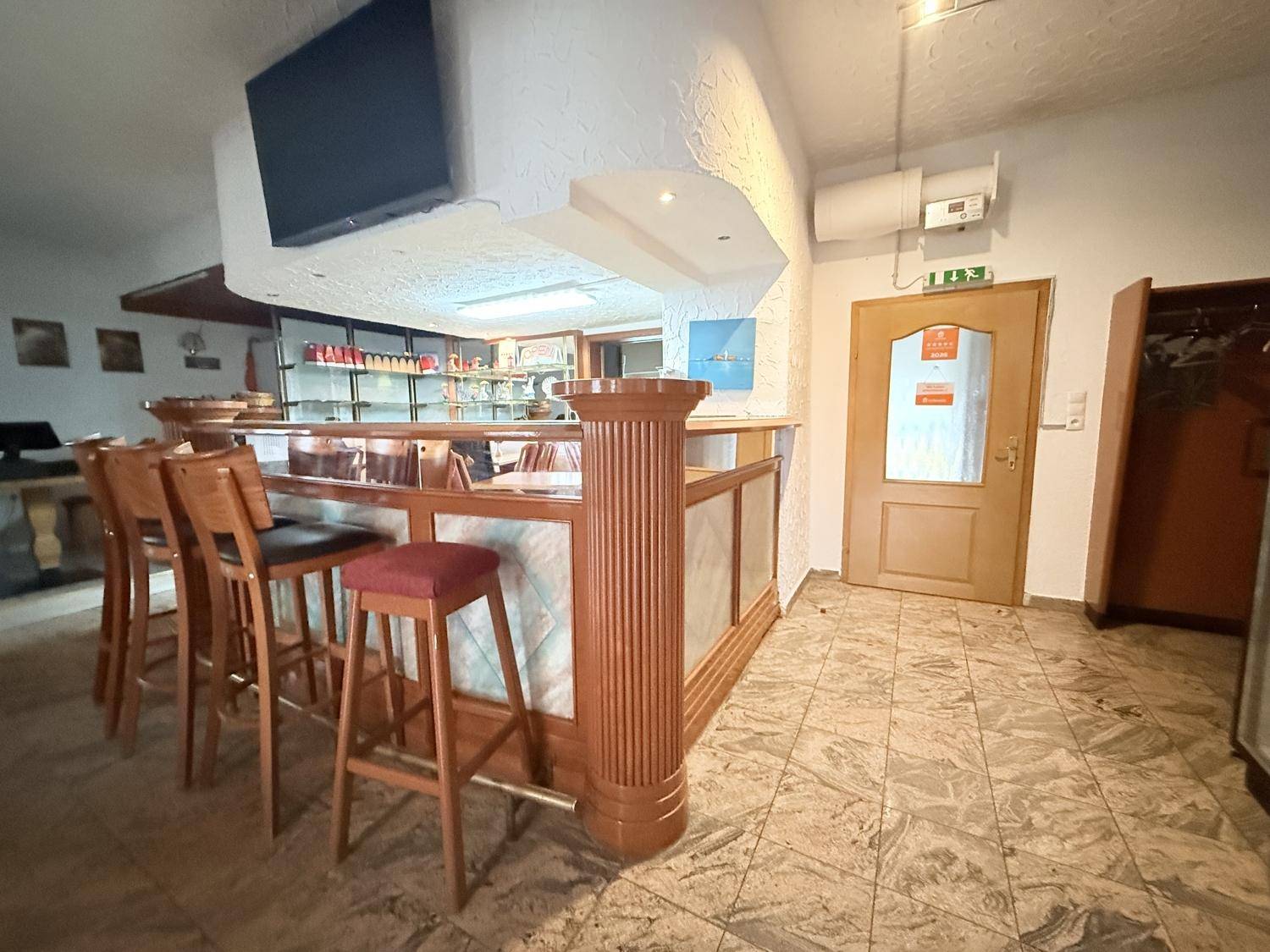 Barbereich mit Holzelementen, Barhockern und einem Fernseher an der Wand.