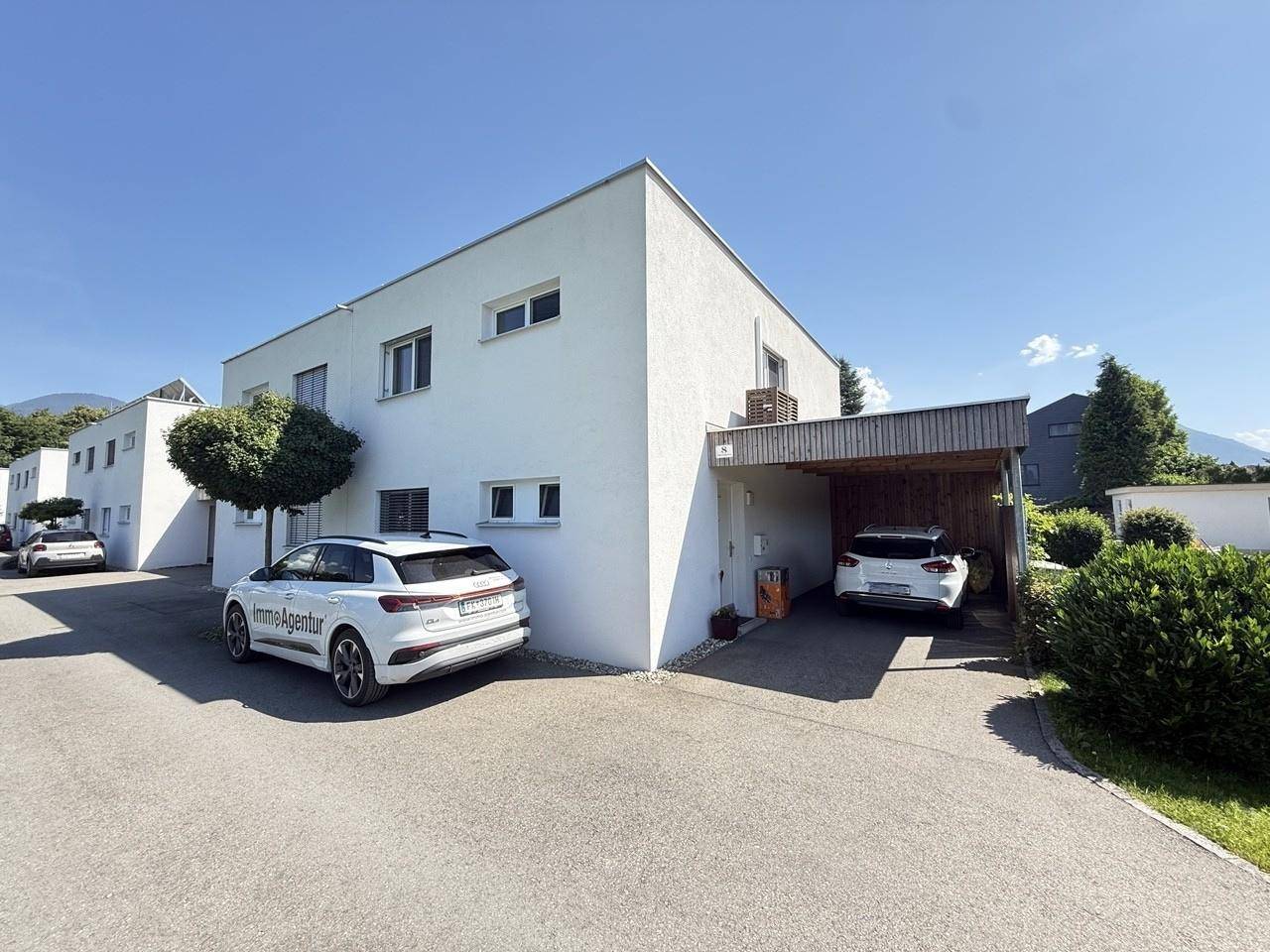 Die moderne Hausfassade mit Carport und Stellplätzen bietet bequeme Parkmöglichkeiten.