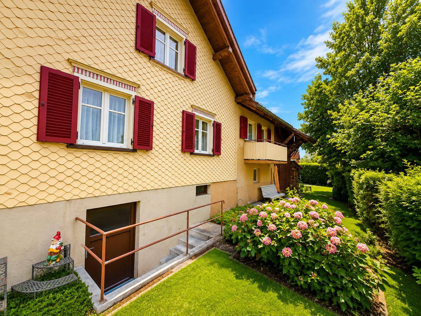 Seitlicher Gartenbereich mit blühenden Hortensien und Zugang zum Kellergeschoss des Hauses.