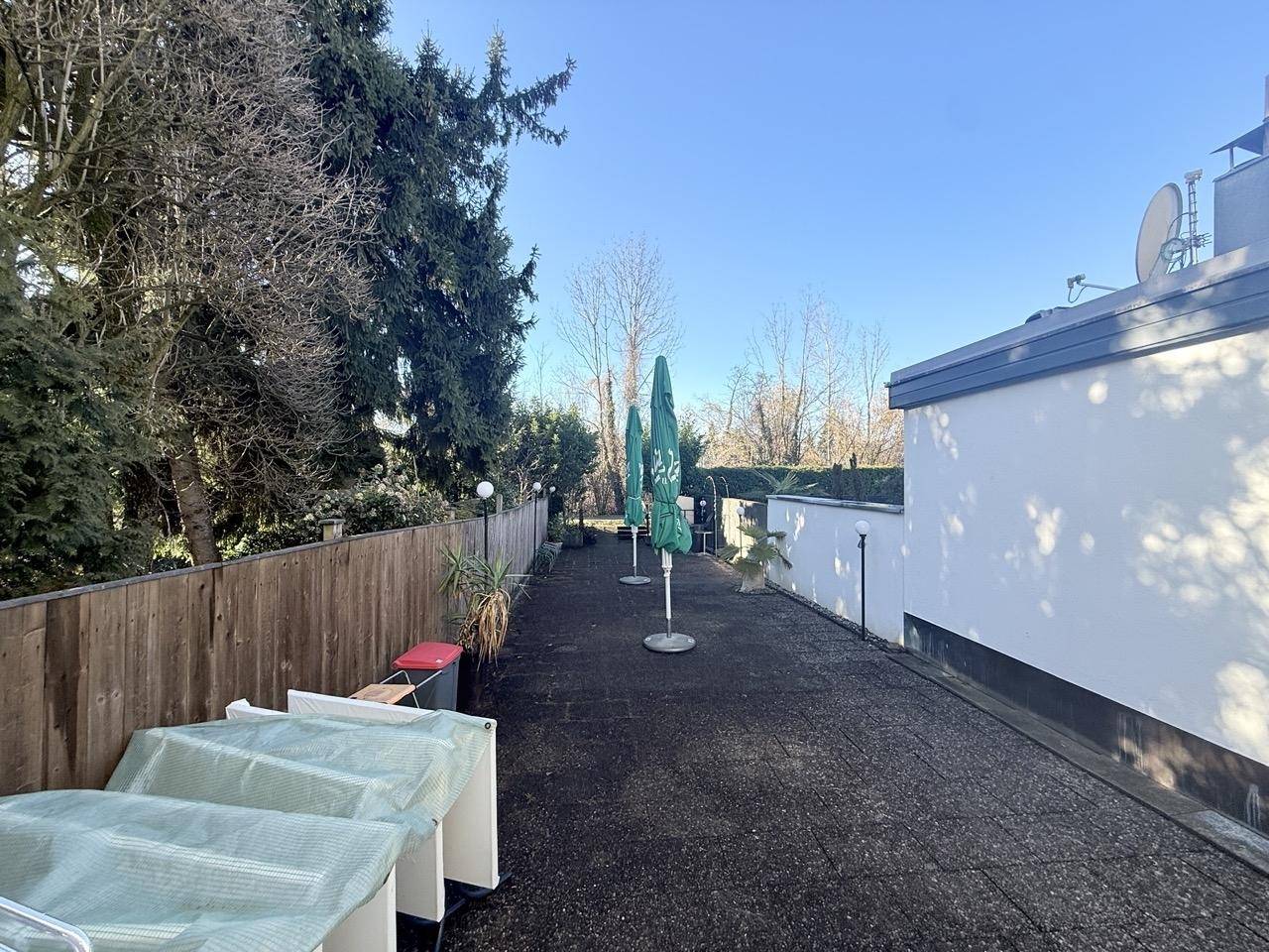 Weitläufige gepflasterte Terrasse mit Sonnenschirmen und umgebender Vegetation.