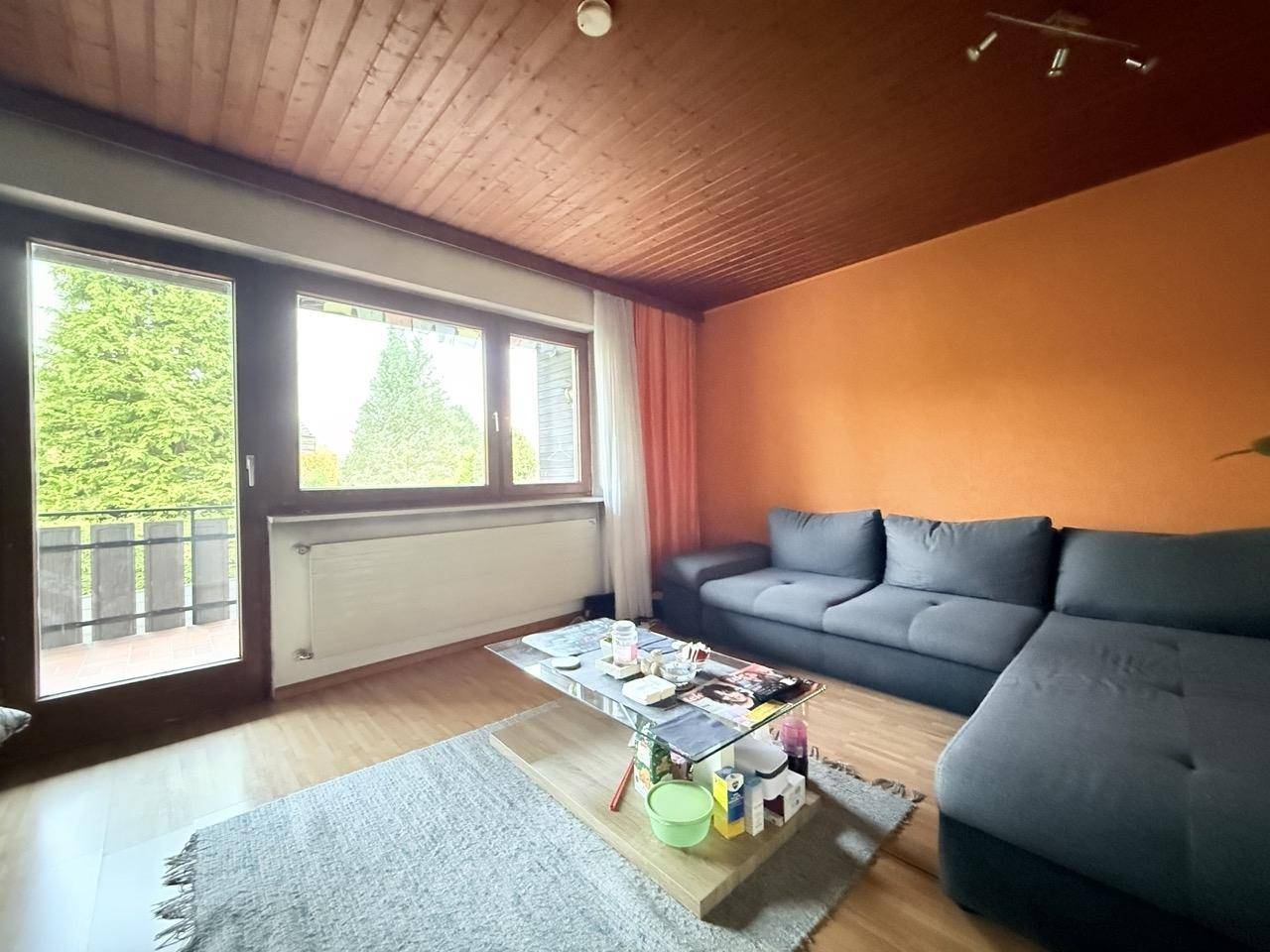 Wohnzimmer mit Sofa, Laminatboden und Zugang zu einem Balkon, der zum Entspannen einlädt.