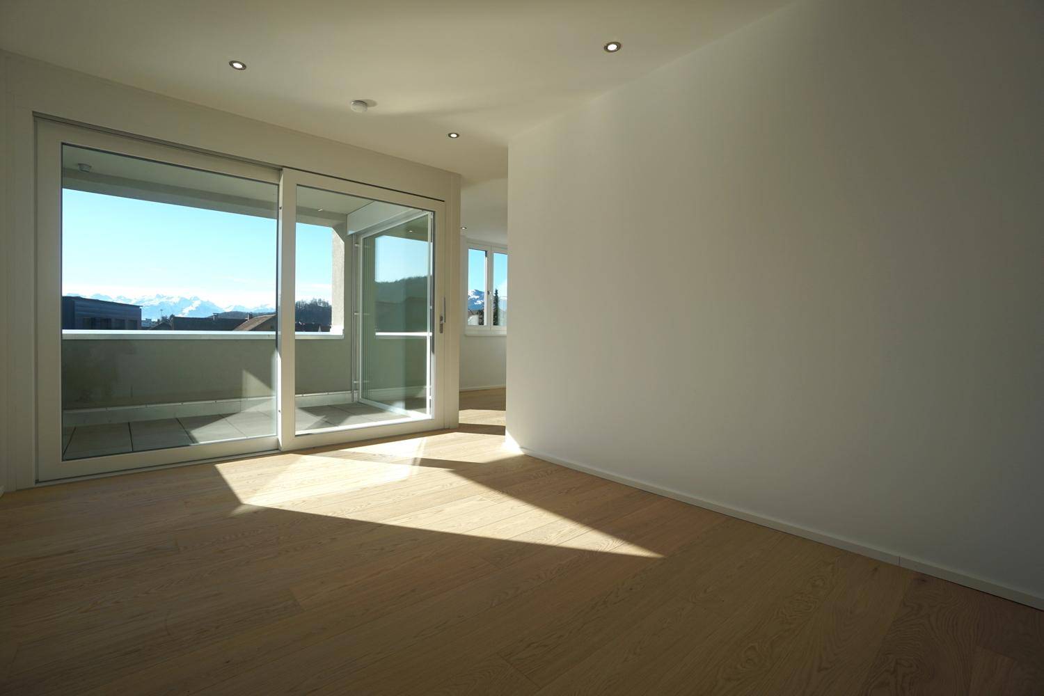 Geräumiger, heller Wohnbereich mit Holzboden und Schiebetüren, die einen weiten Bergblick bieten.