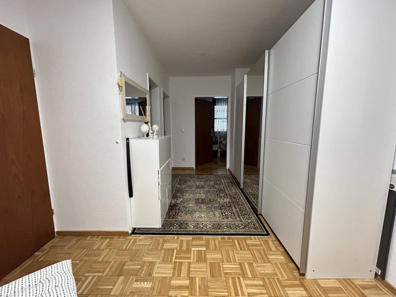 Geräumiger Flur mit Parkettboden und großen Spiegelschränken für zusätzlichen Stauraum.