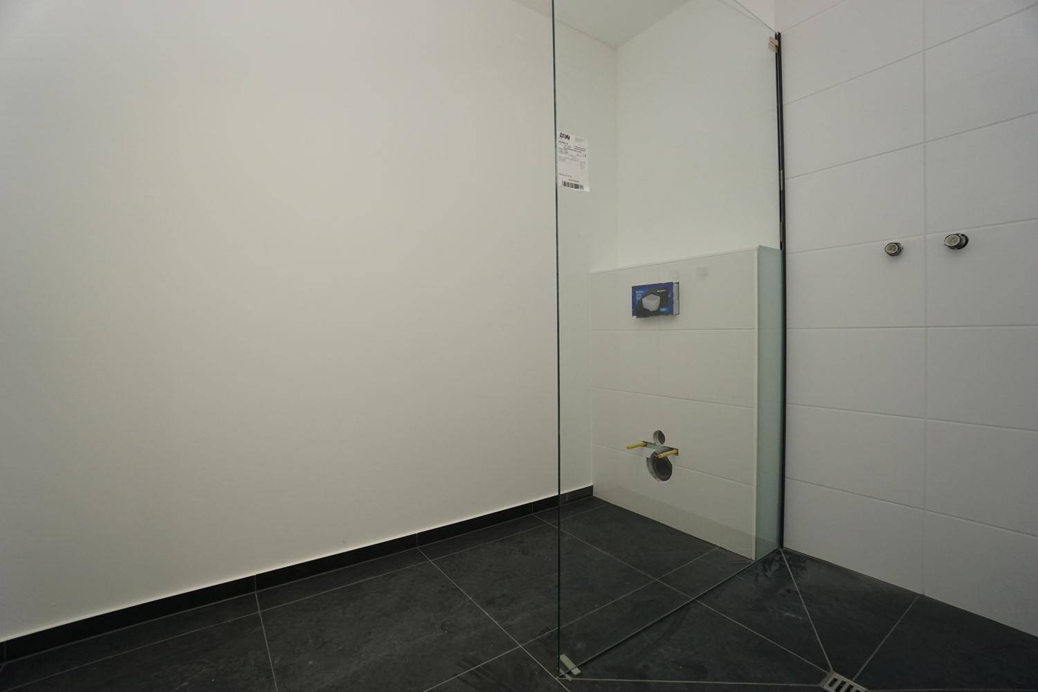 Geräumige Dusche im Badezimmer mit Glasabtrennung und Vorbereitung für Armaturen.