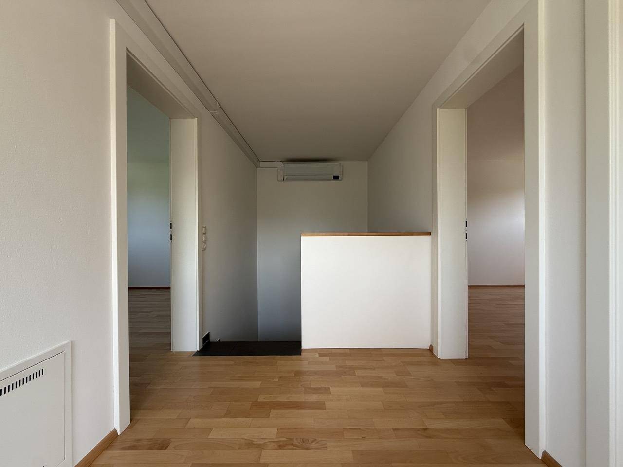 Heller Flur mit Holzfußboden, der zu den verschiedenen Räumen des Hauses führt.