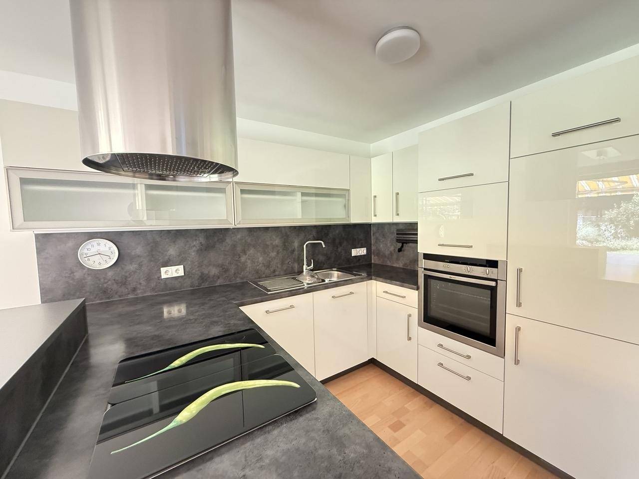 Gut ausgestattete moderne Küche mit Induktionskochfeld, Backofen und Dunstabzugshaube.