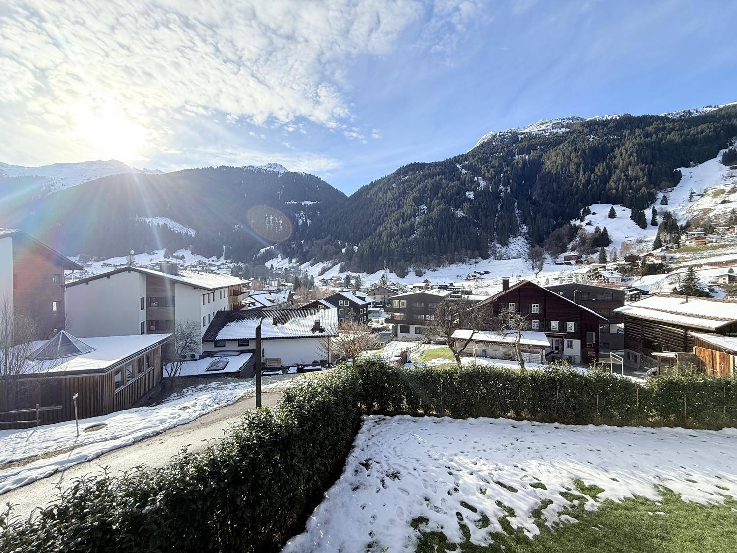 Verschneiter Gartenbereich mit Hecke und weitem Blick auf die winterliche Berglandschaft.
