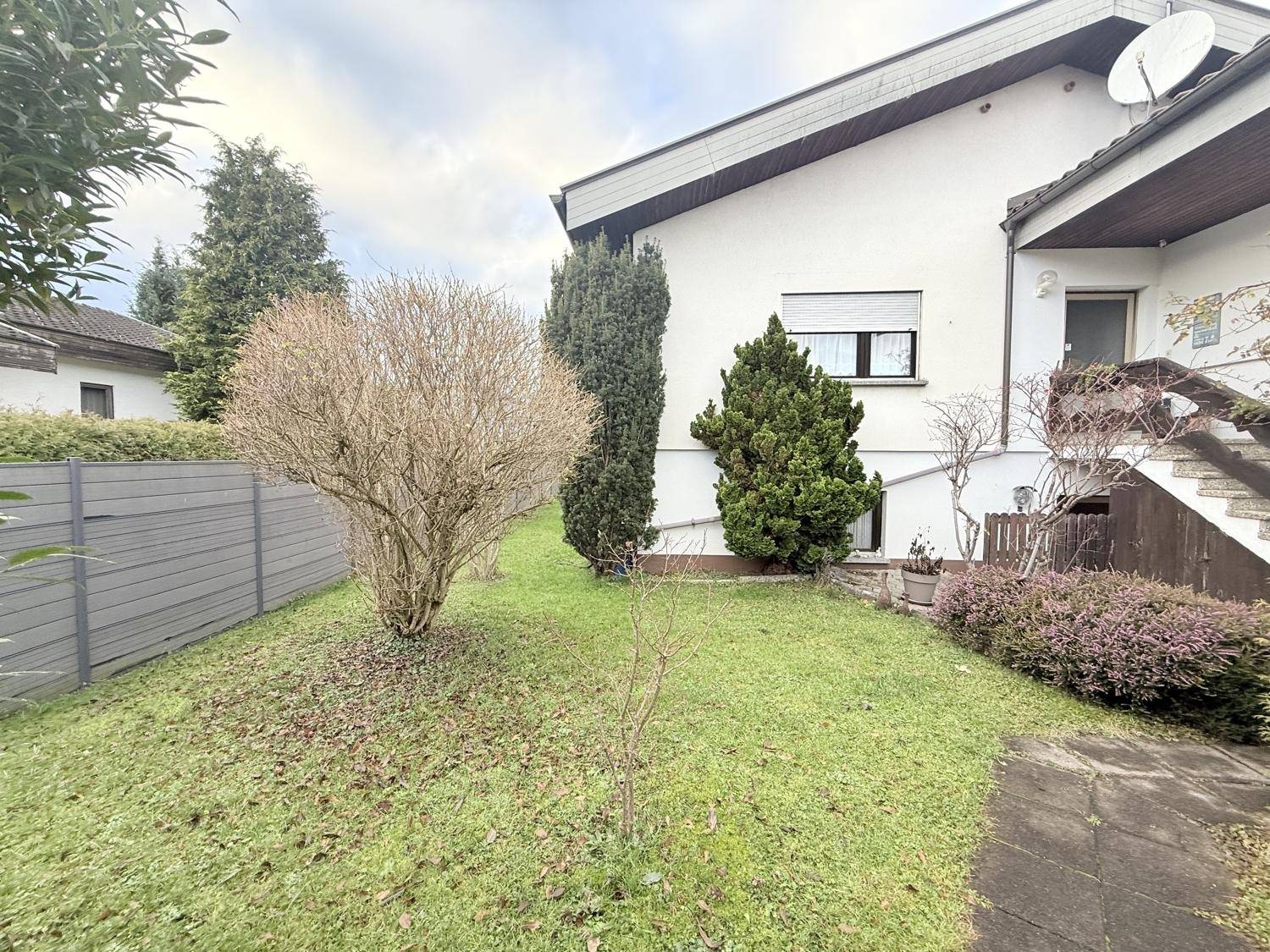 Gepflegter Gartenbereich mit Rasen und Büschen, der zum Entspannen im Freien einlädt.
