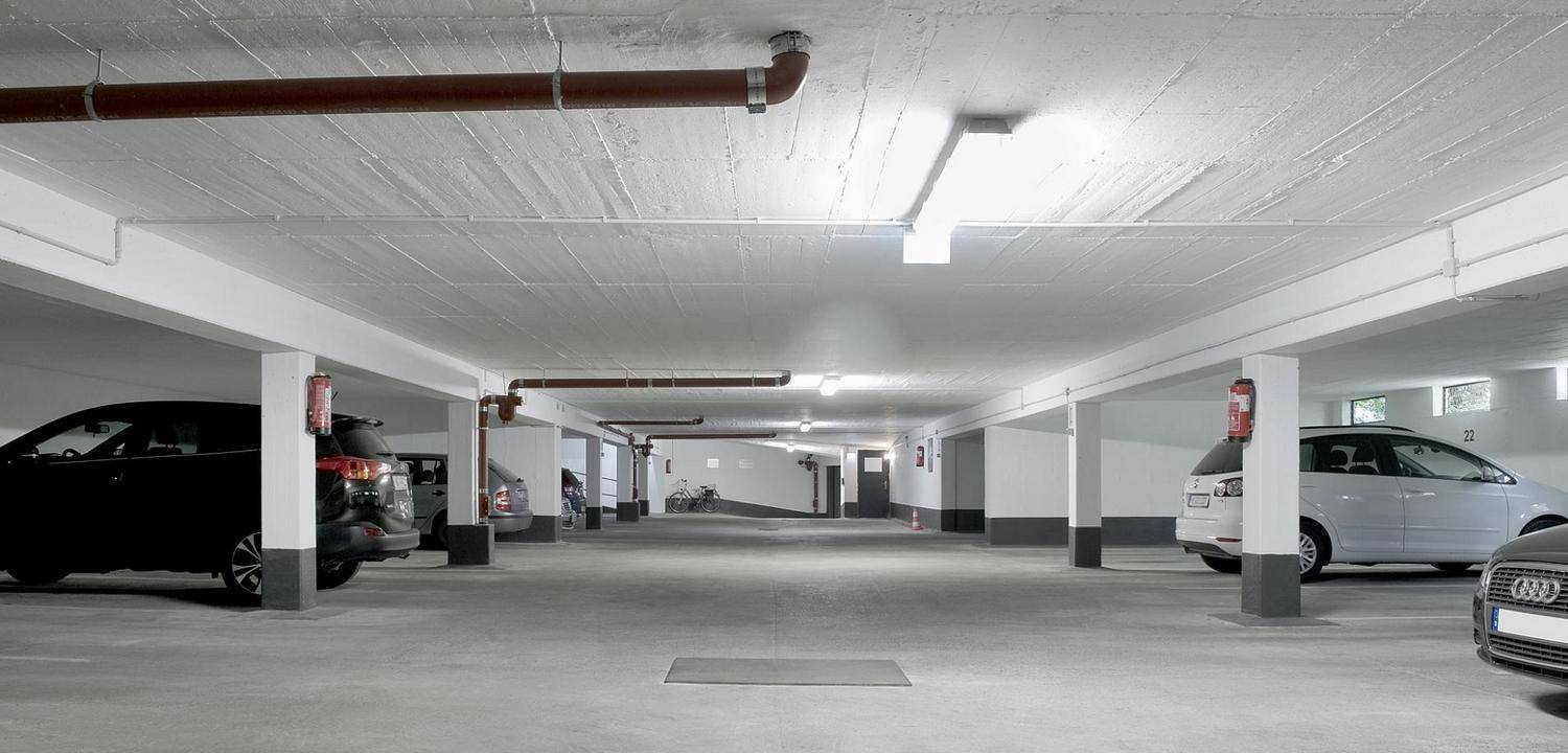 Helle und saubere Tiefgarage mit Betonboden, Säulen und ausreichend Platz für Fahrzeuge.