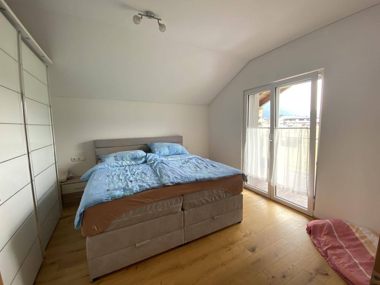 Geräumiges Schlafzimmer mit Doppelbett, Schrank und Balkonzugang.